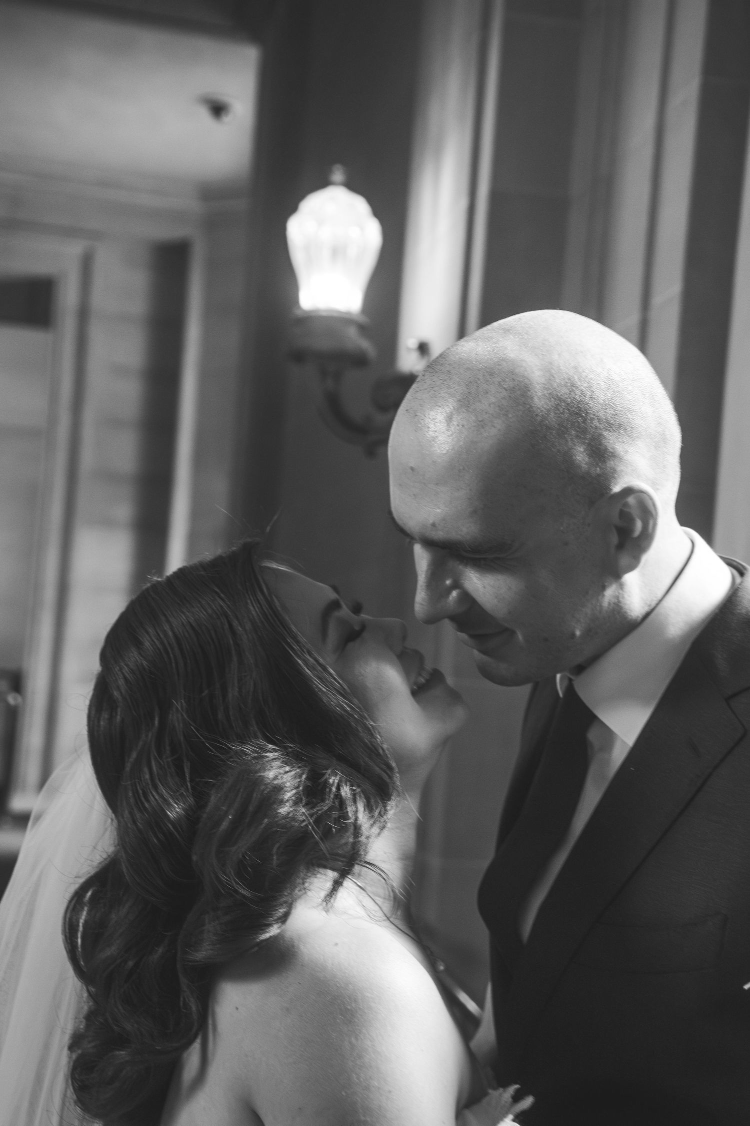 Black and white candid wedding photo capturing intimate moment between couple.