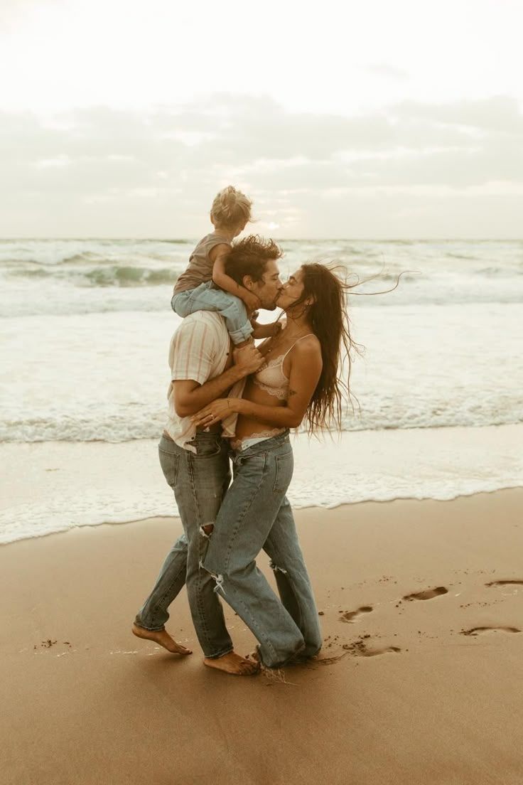 Family playing and dancing together on beach at sunset.