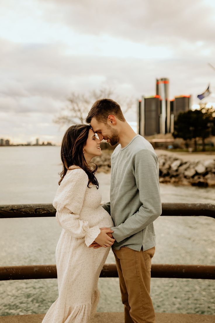 Romantic couple embracing by the water during sunset in a serene coastal setting.