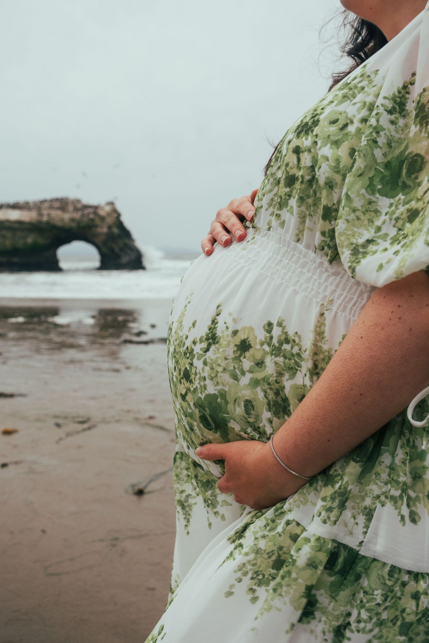 Close-up details of a floral patterned dress against a beach landscape backdrop.