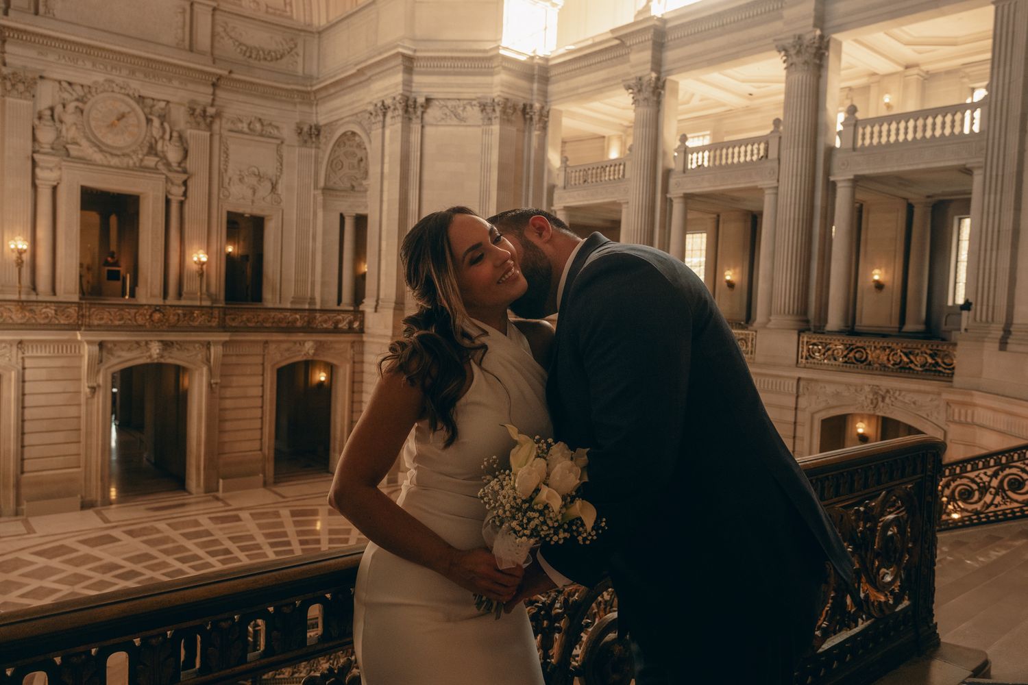 Wedding couple poses in an elegant hallway with classical architecture and dramatic lighting.
