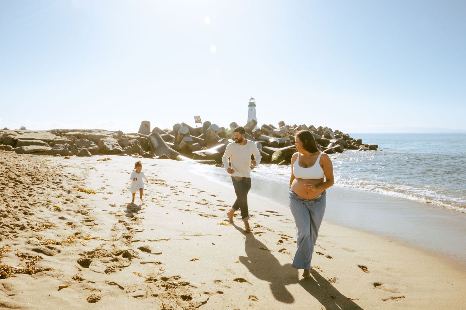 A couple walks along a scenic beach at sunset creating footprints in the sand.