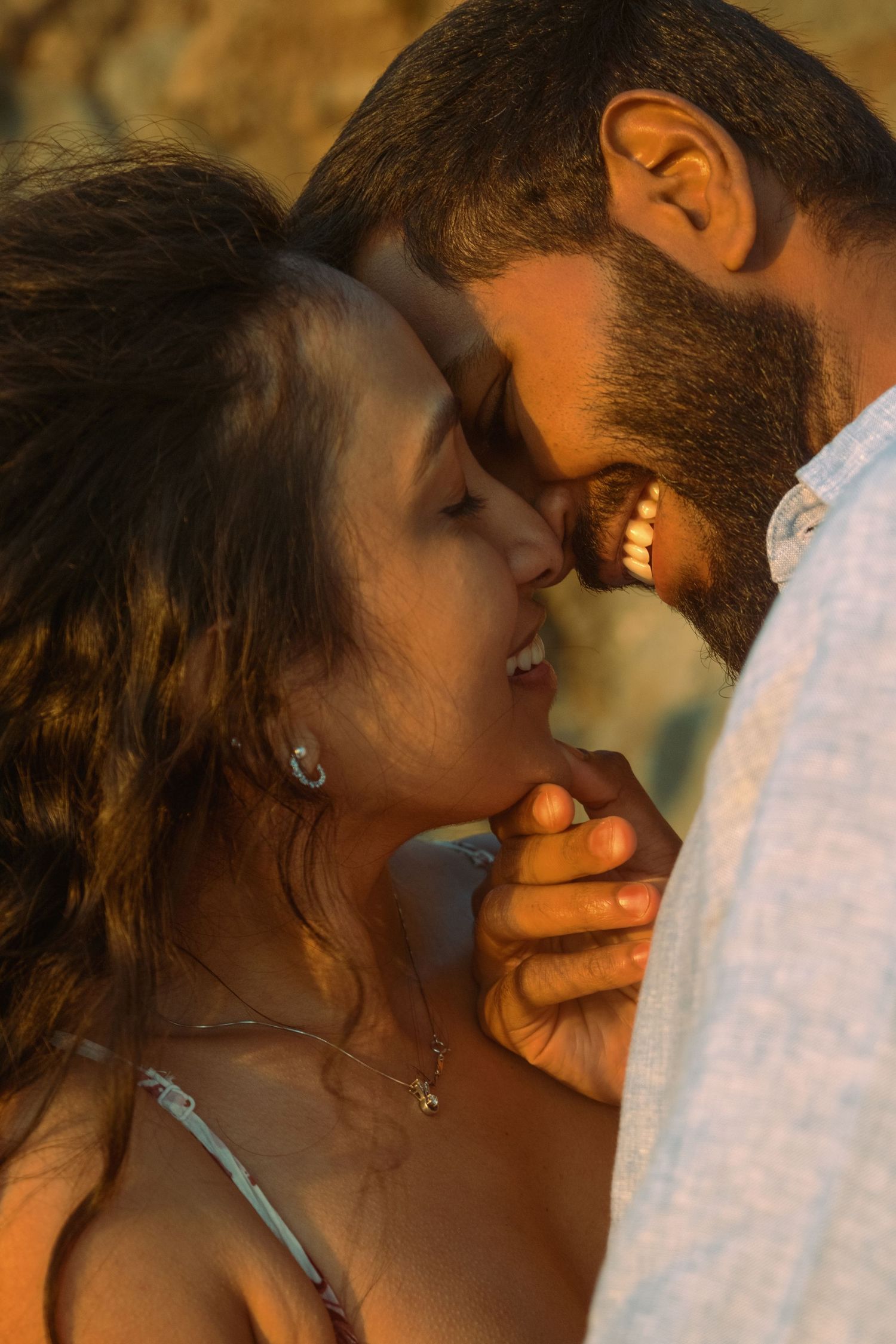 Intimate close-up of couple sharing tender moment in golden sunlight.