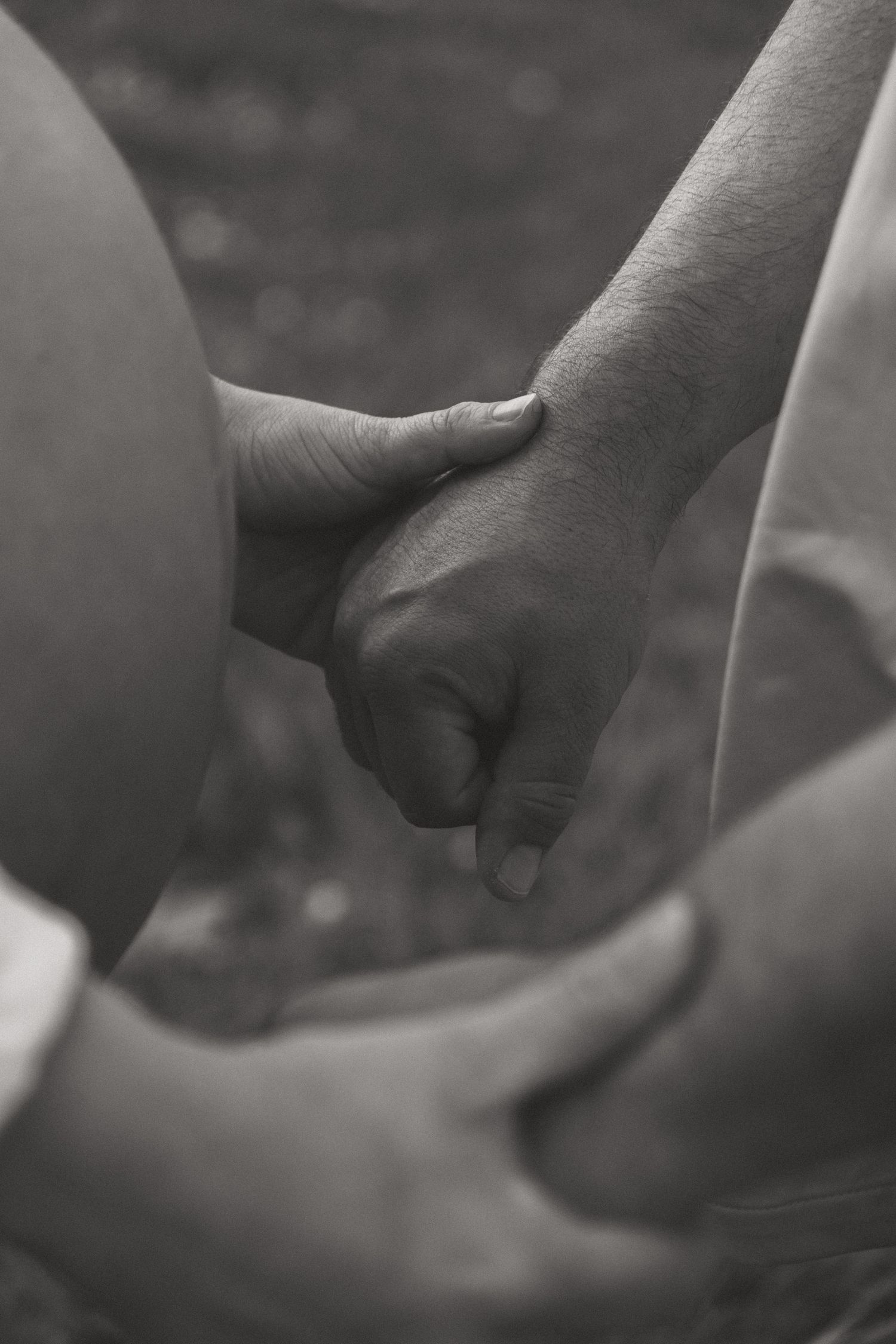Black and white close-up of hands gently touching.