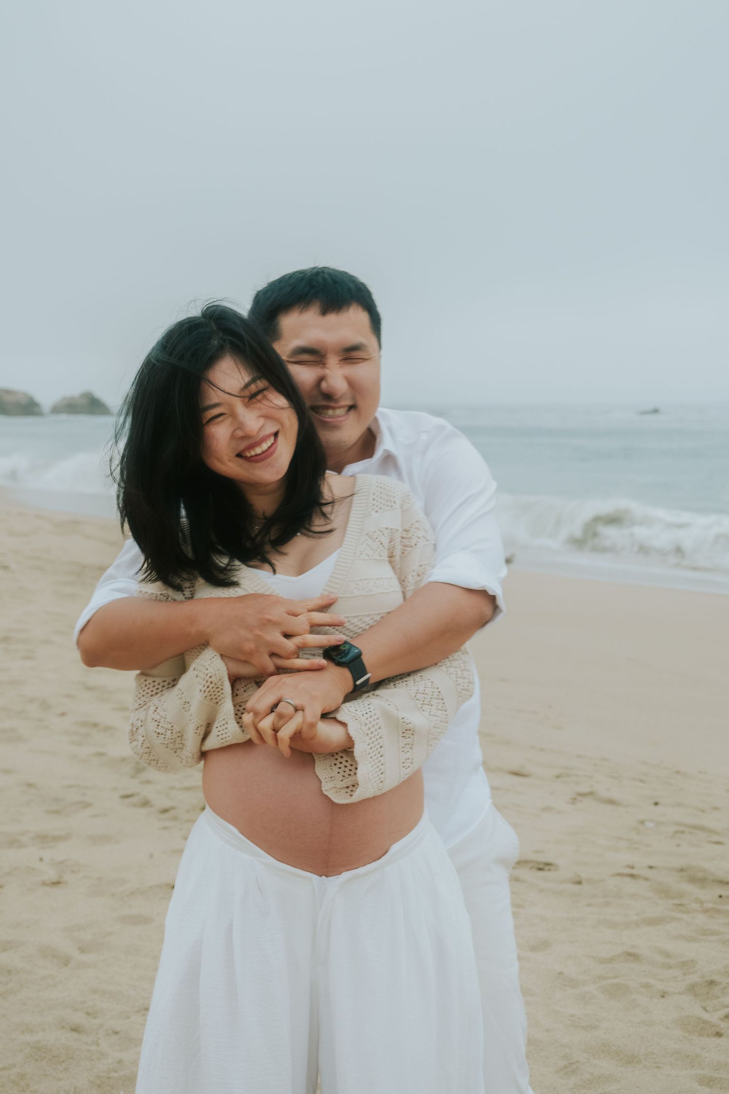 A couple shares an intimate embrace on a sandy beach.