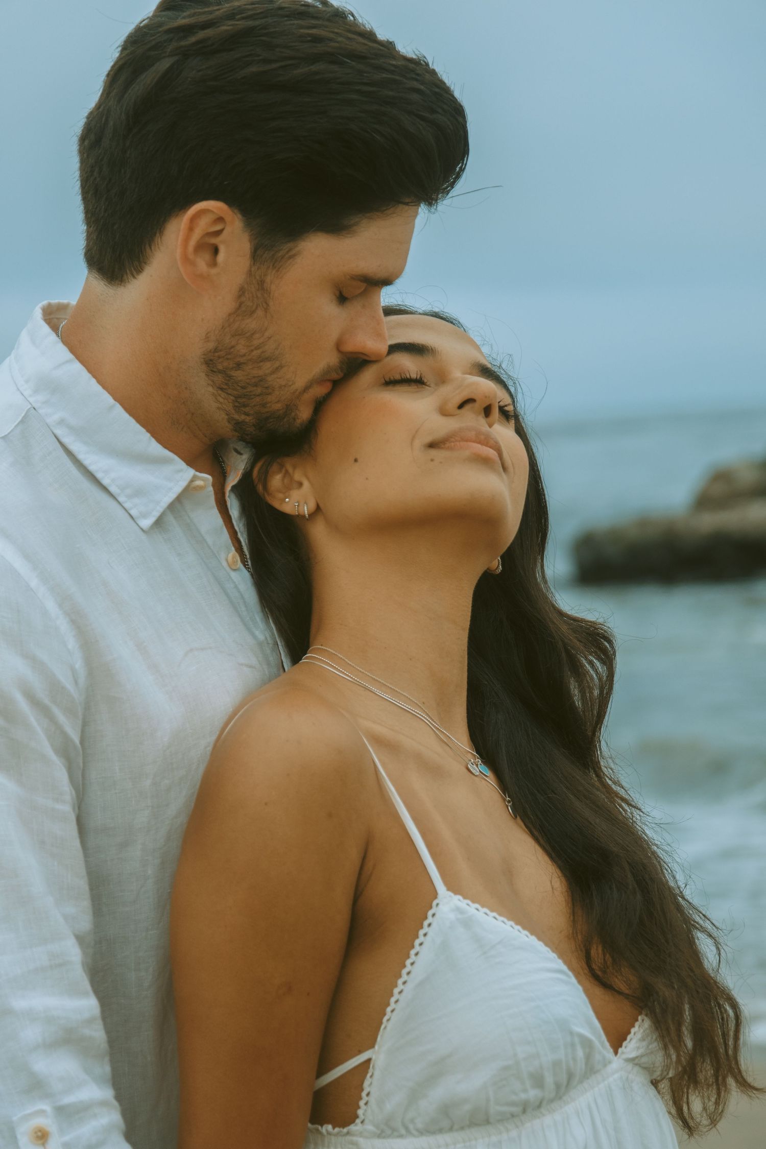 Intimate close-up of a couple sharing a romantic moment by the ocean.