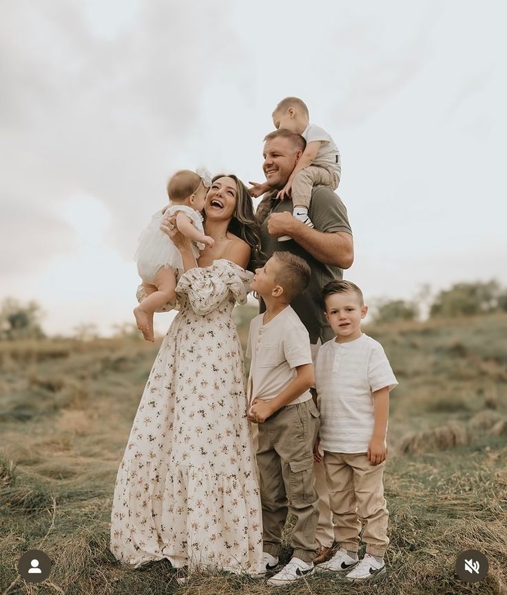 Family photoshoot in a grassy field showing playful candid moments and laughter.