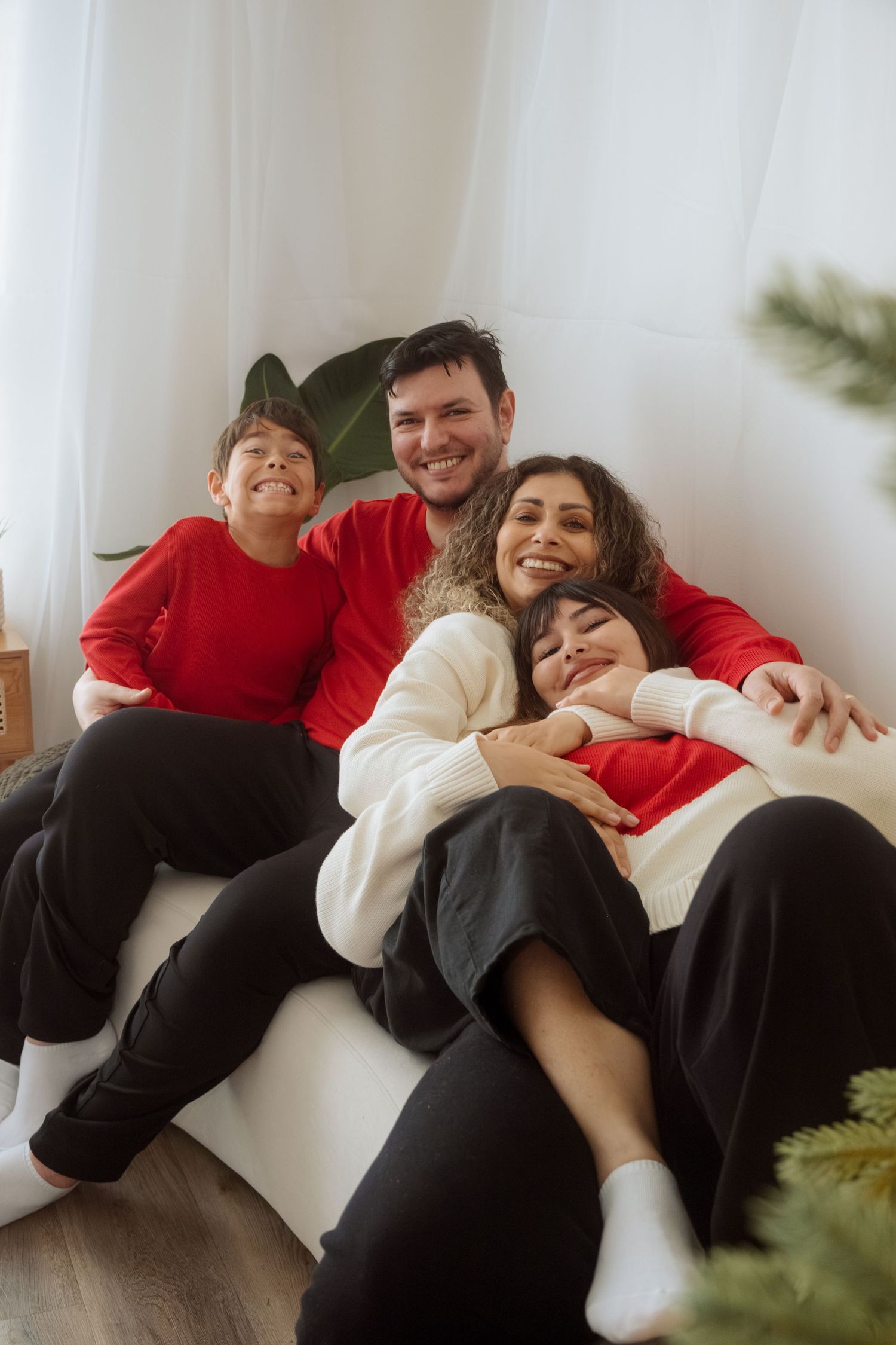 Group relaxing and laughing together on white couch during festive photo session.
