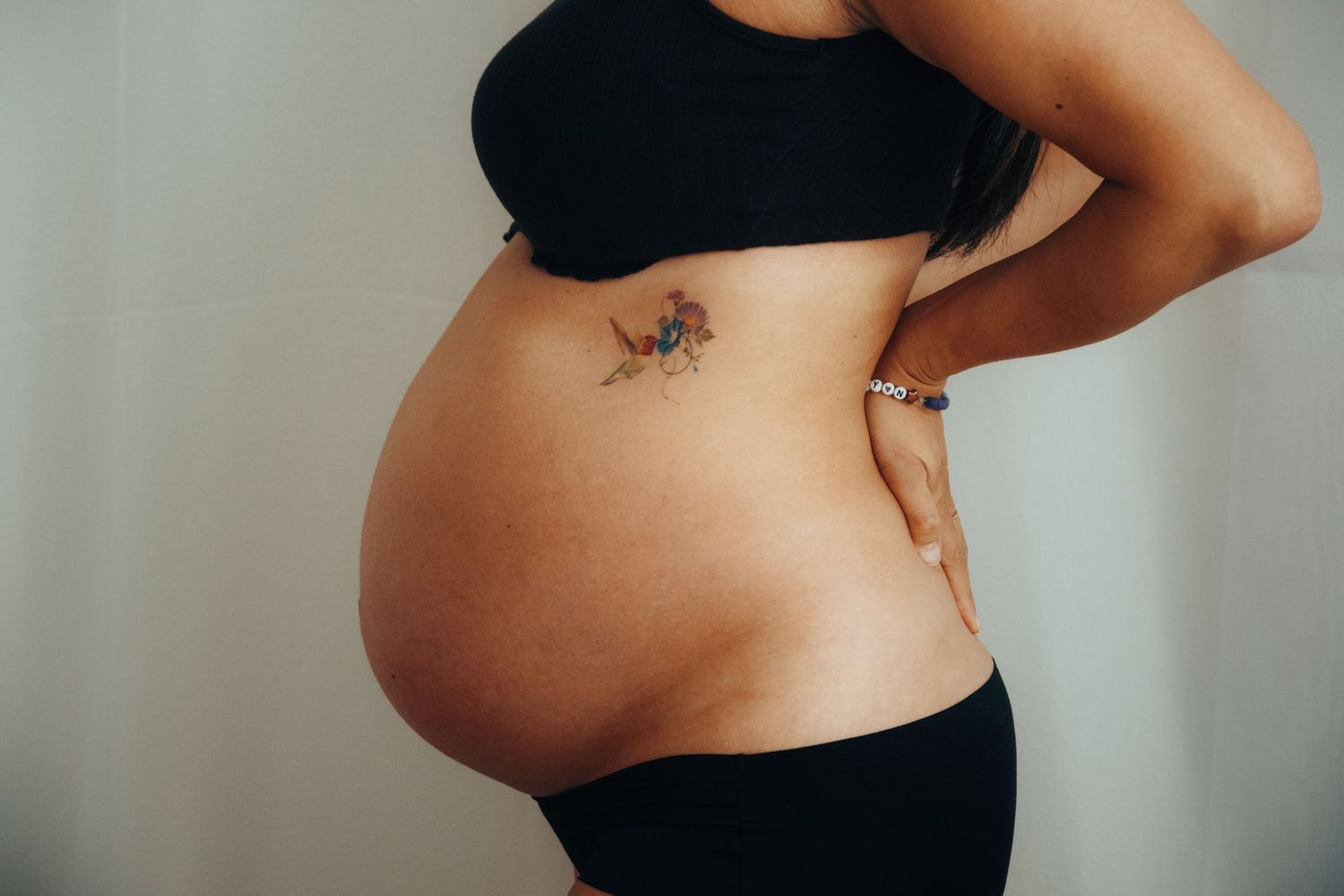 Intimate maternity photoshoot showing close-up details of a pregnant belly in casual denim.