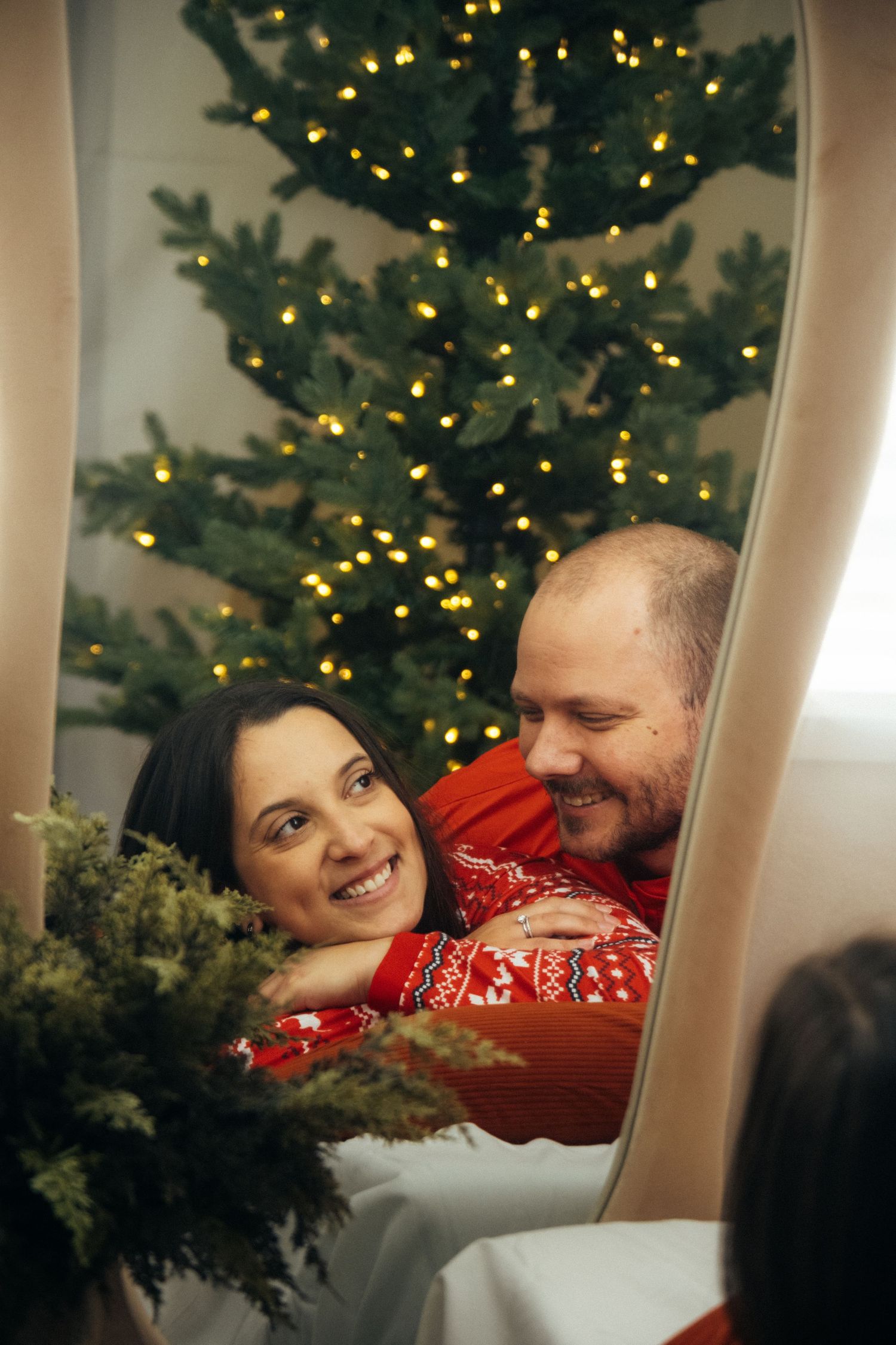 Romantic holiday moment reflected in mirror with Christmas tree lights twinkling in background.