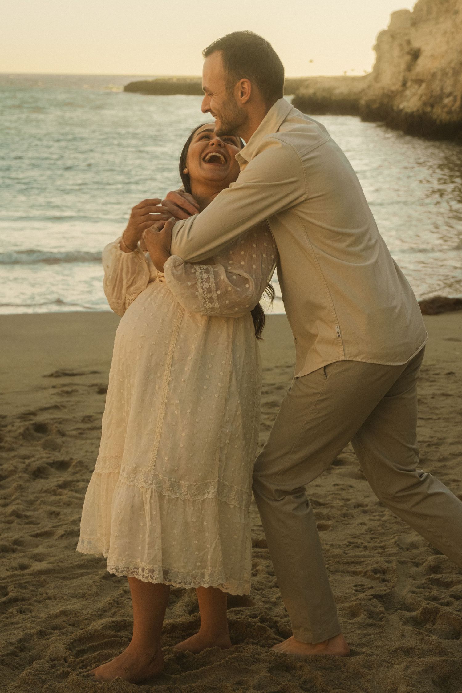 A romantic moment captured between two people on a beach at sunset.