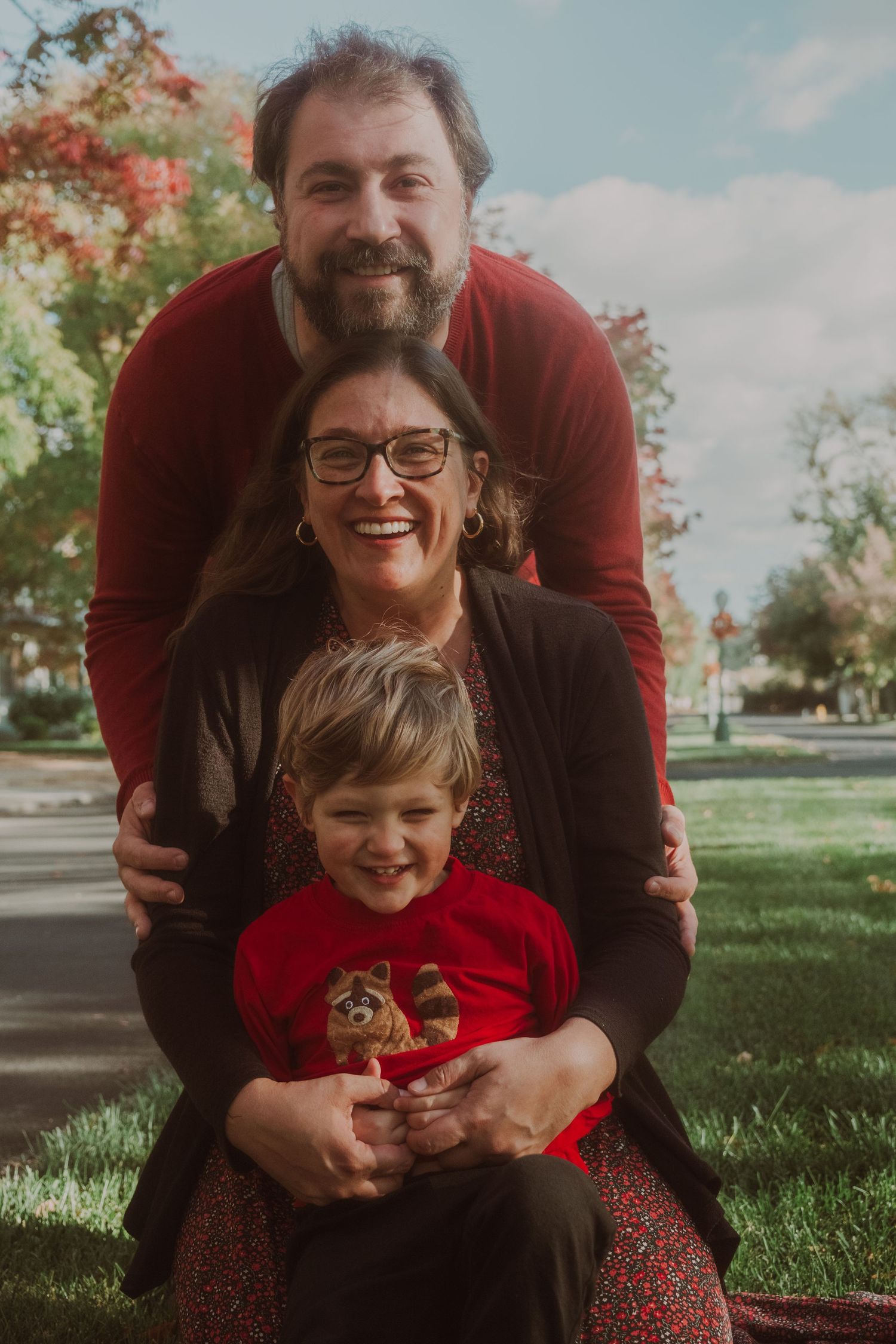 A joyful outdoor family portrait session with everyone laughing on green grass.