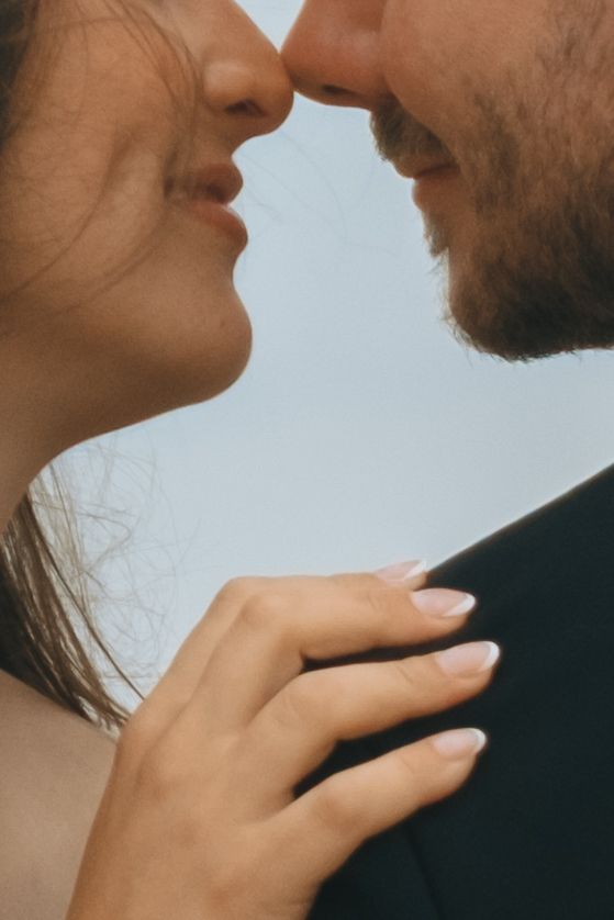 Close-up intimate portrait of a couple against light background.