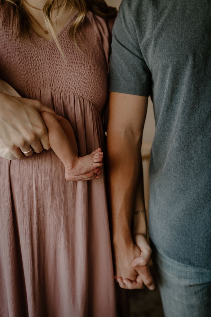 Close-up view of couple holding hands, wearing pink dress and gray shirt in intimate moment.