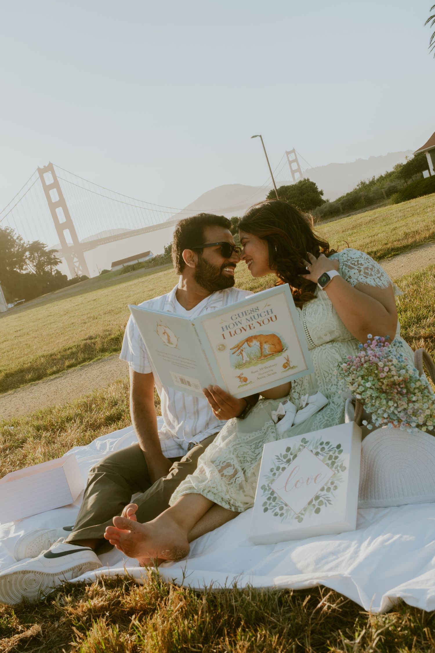 Couple reading together on blanket with Golden Gate Bridge in background.