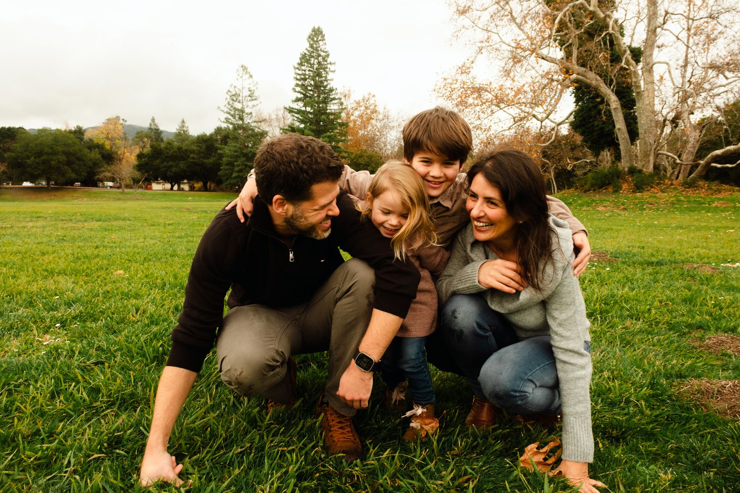 Family lying together on grass sharing joyful moments outdoors.