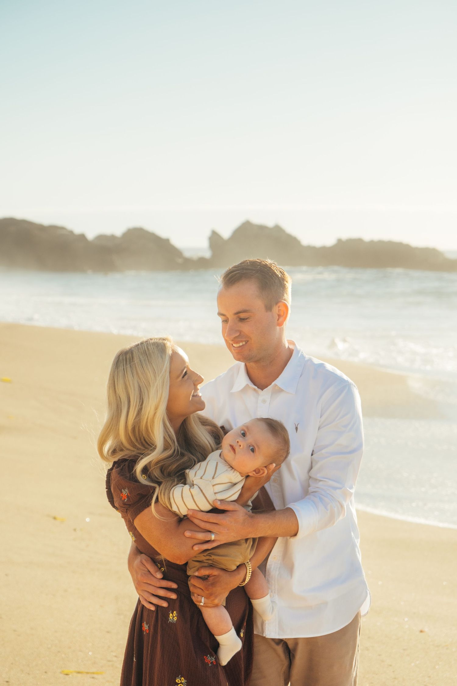Family shares tender moments together during a sunset photoshoot at the beach.