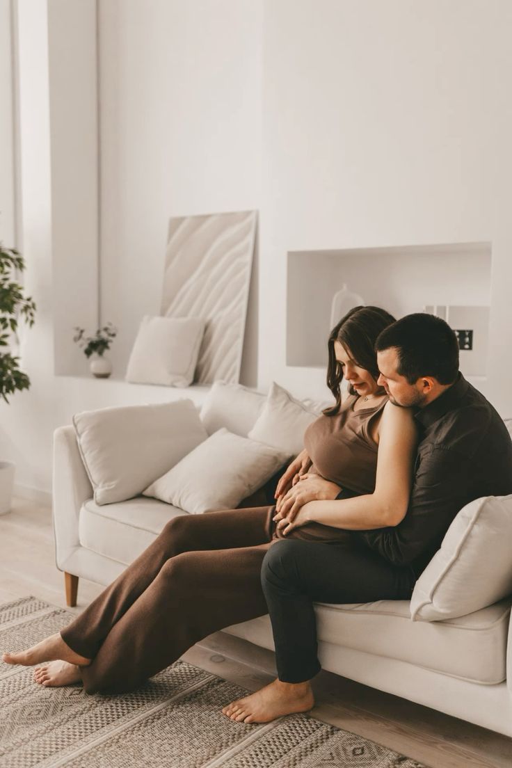 Couple relaxing together on white couch during intimate home photoshoot.
