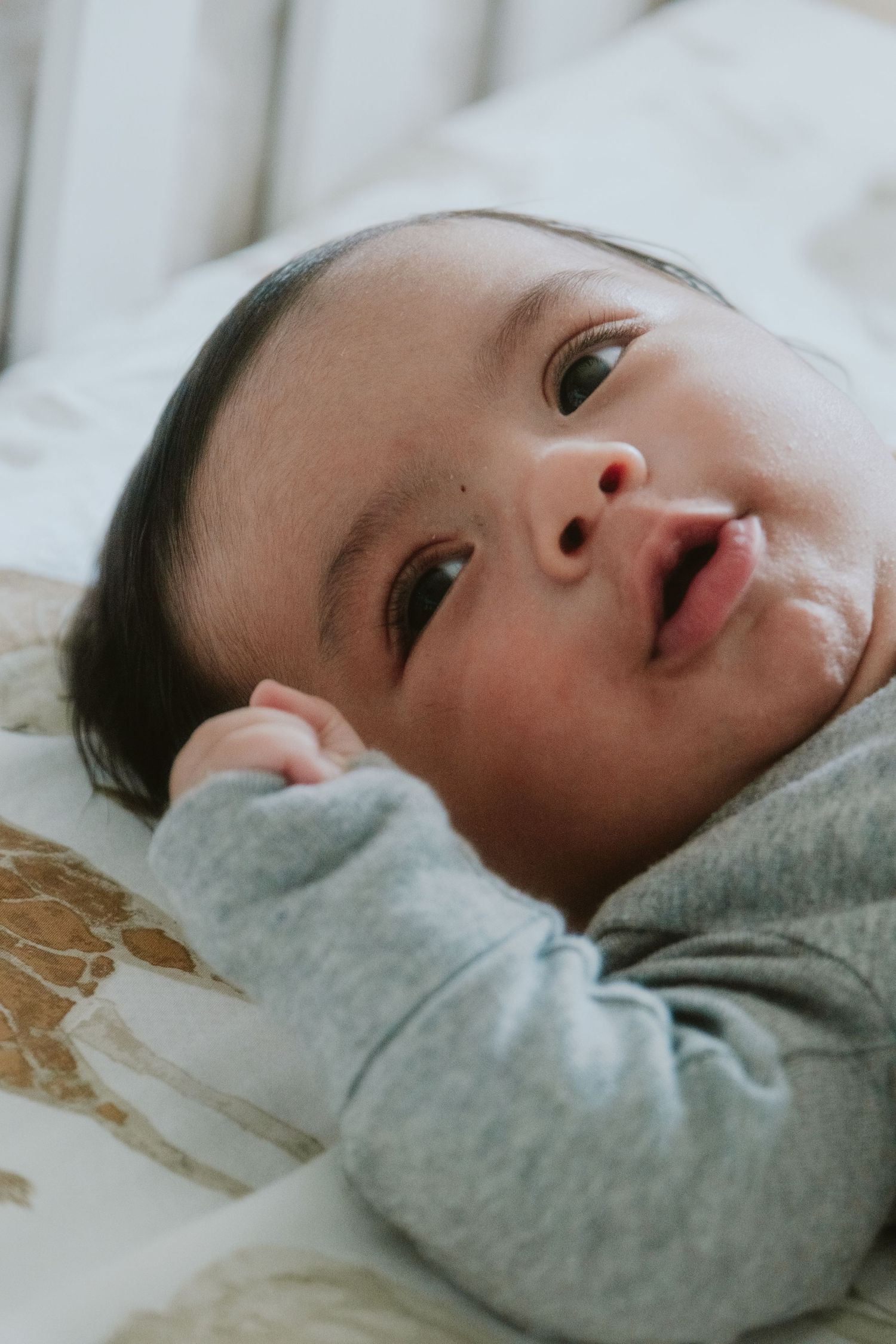 Close-up profile view of a baby lying on soft gray fabric.