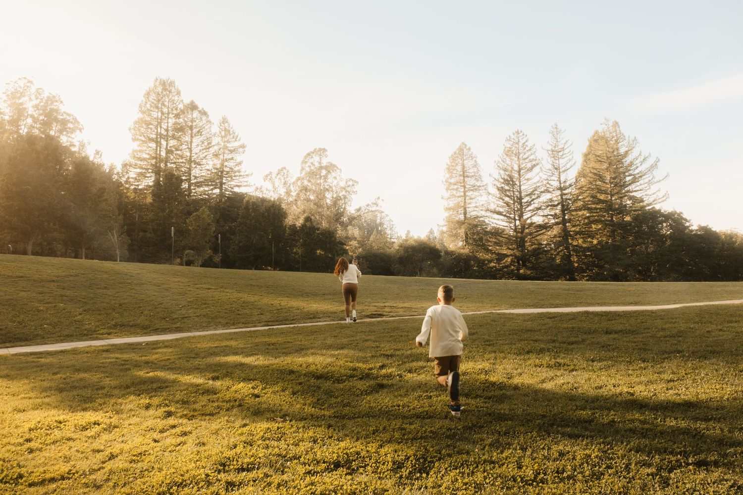 Rolling green hills at sunset with silhouettes of people in the distance.