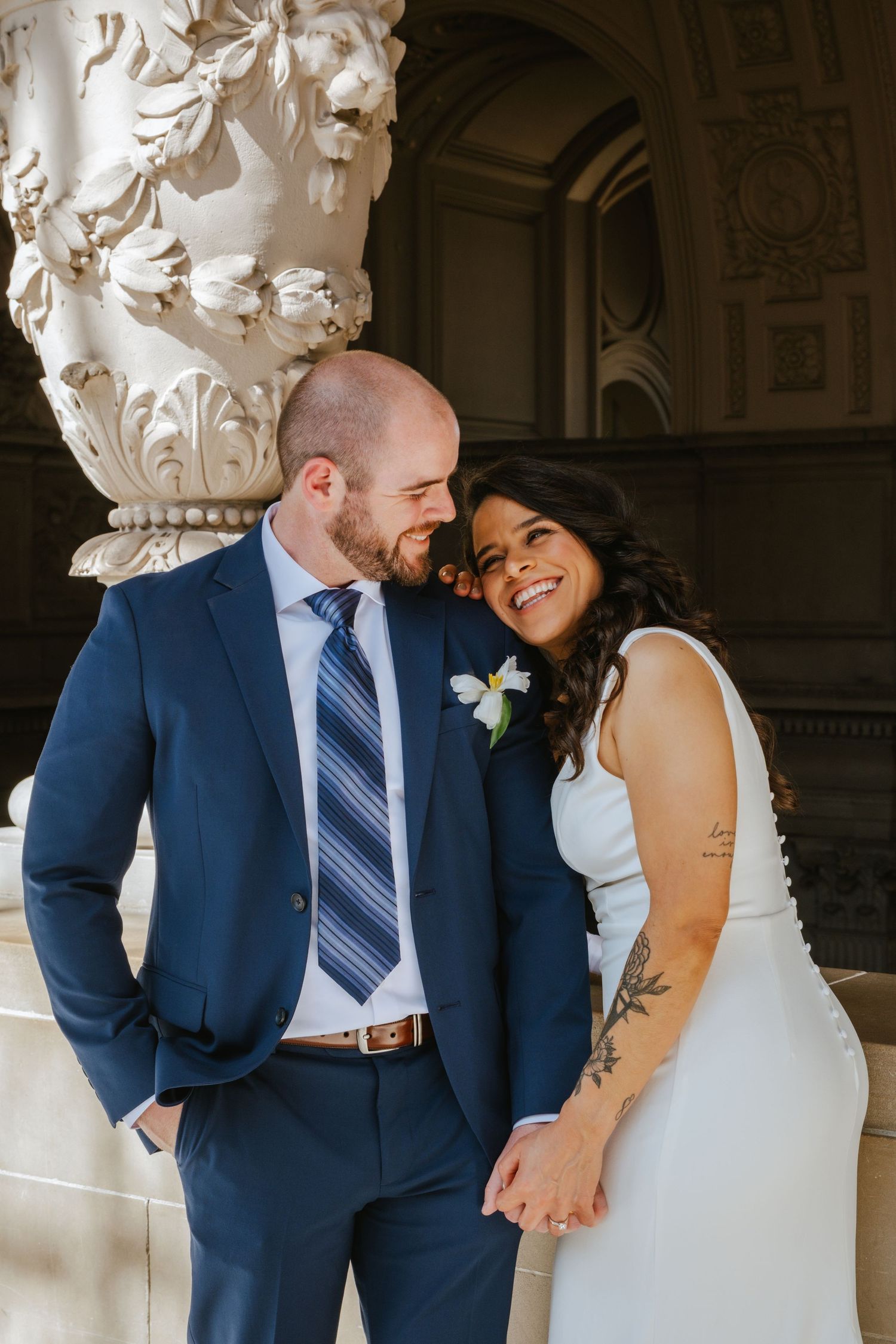 A happy couple shares a joyful moment together on their wedding day at an elegant venue with ornate architectural details.