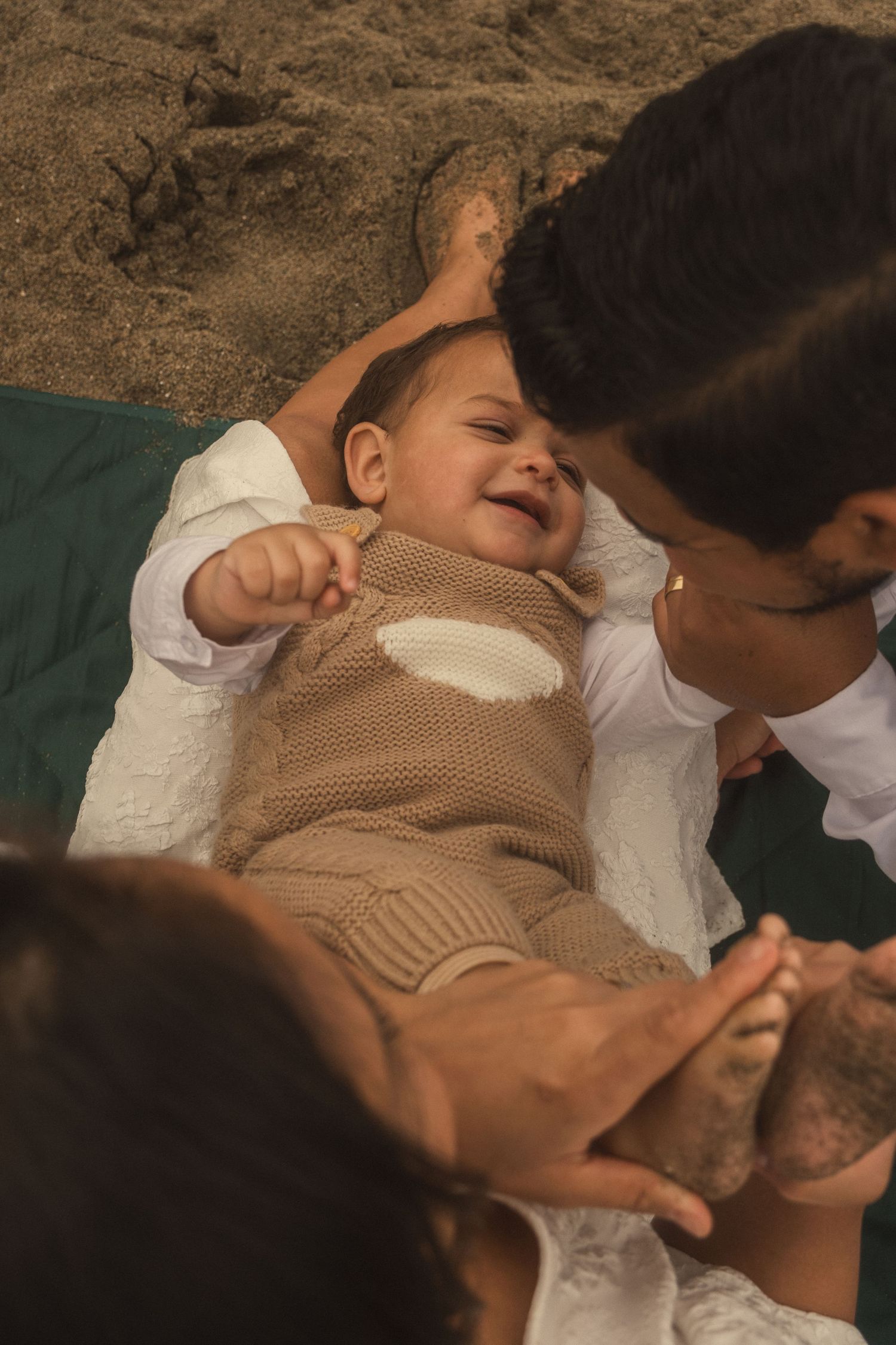 An intimate family moment captured on sandy beach during sunset.