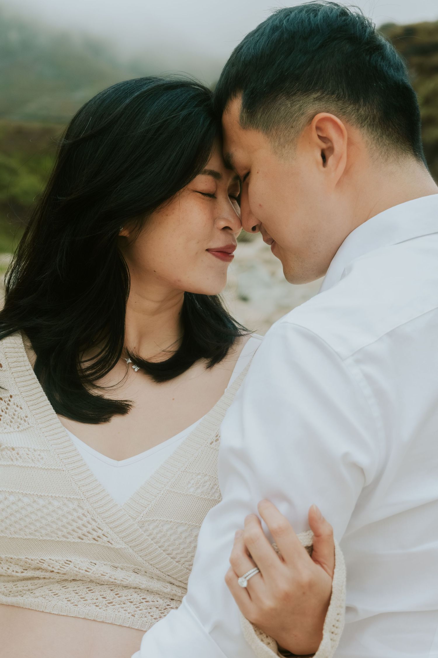 Close-up romantic portrait of a couple in white sharing an intimate moment.