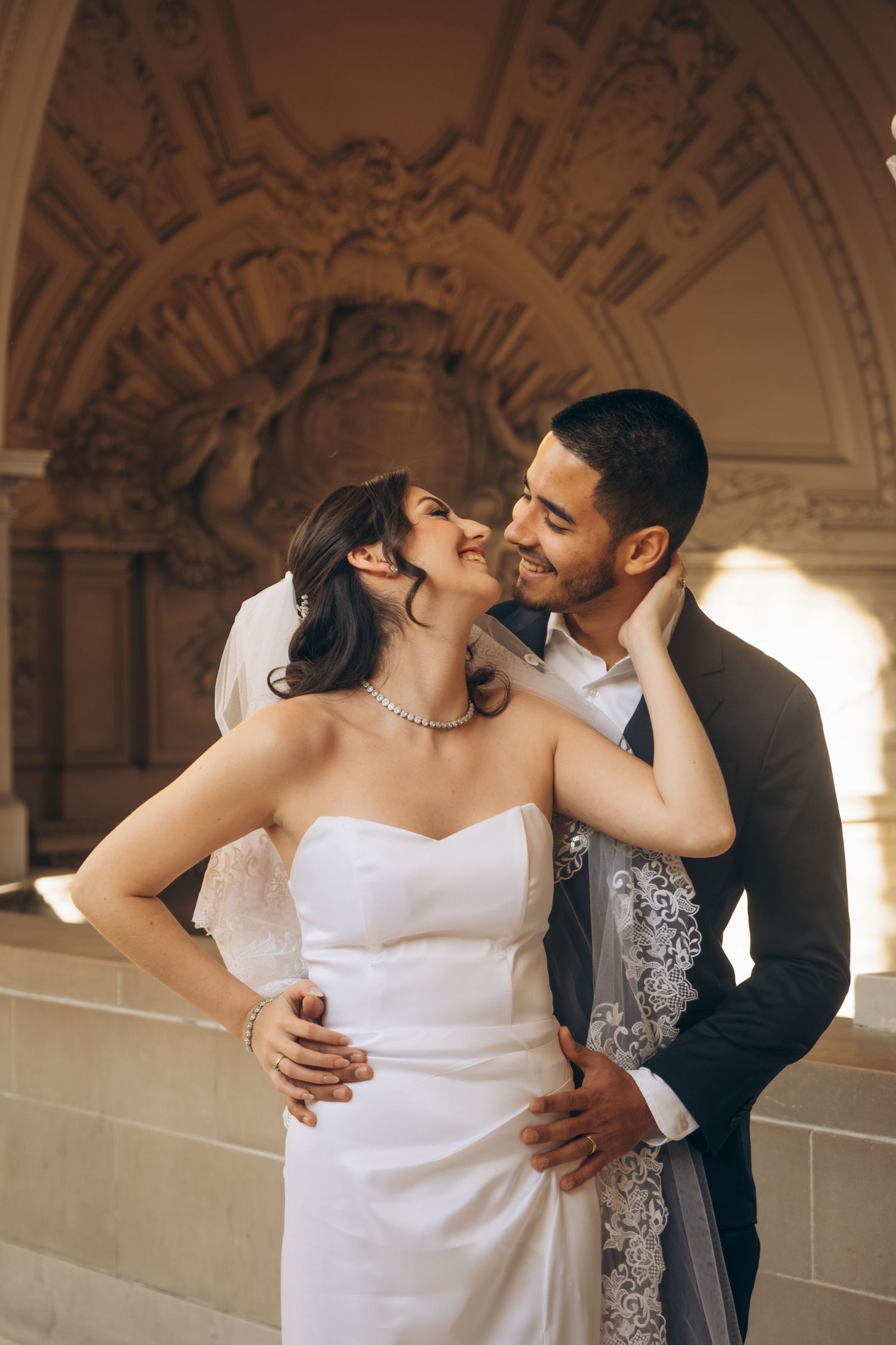 Romantic wedding portraits captured in warm lighting against ornate architectural backdrop.