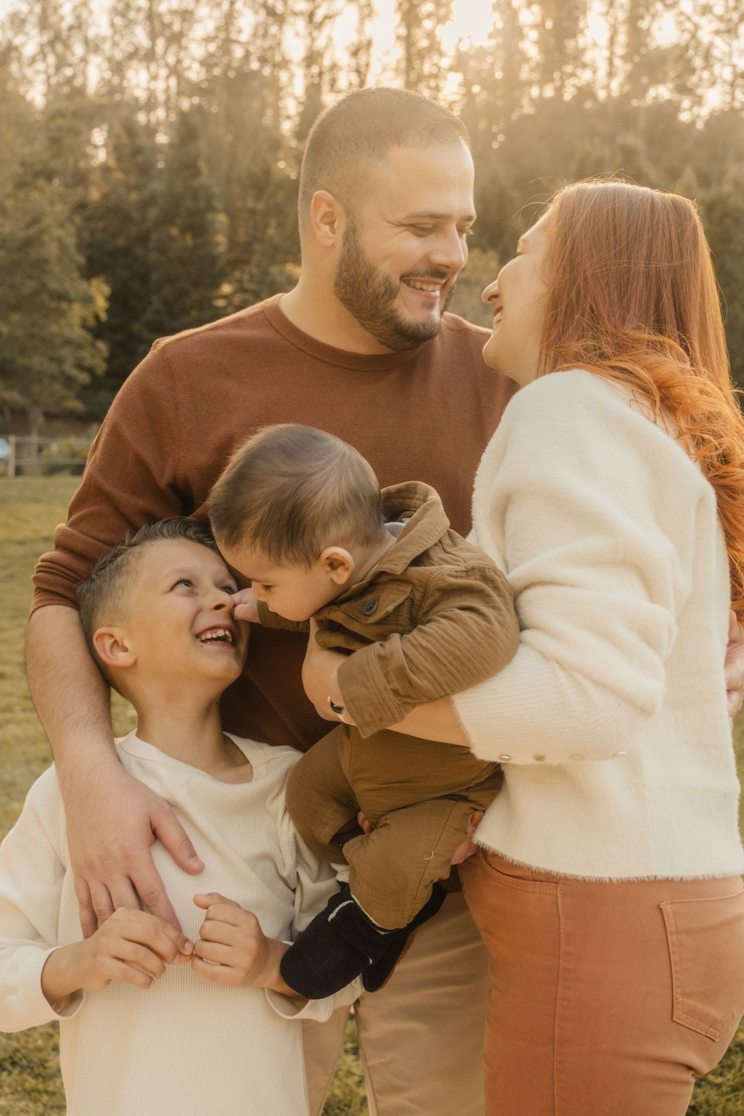 A family shares joyful laughter together during a golden hour photoshoot.