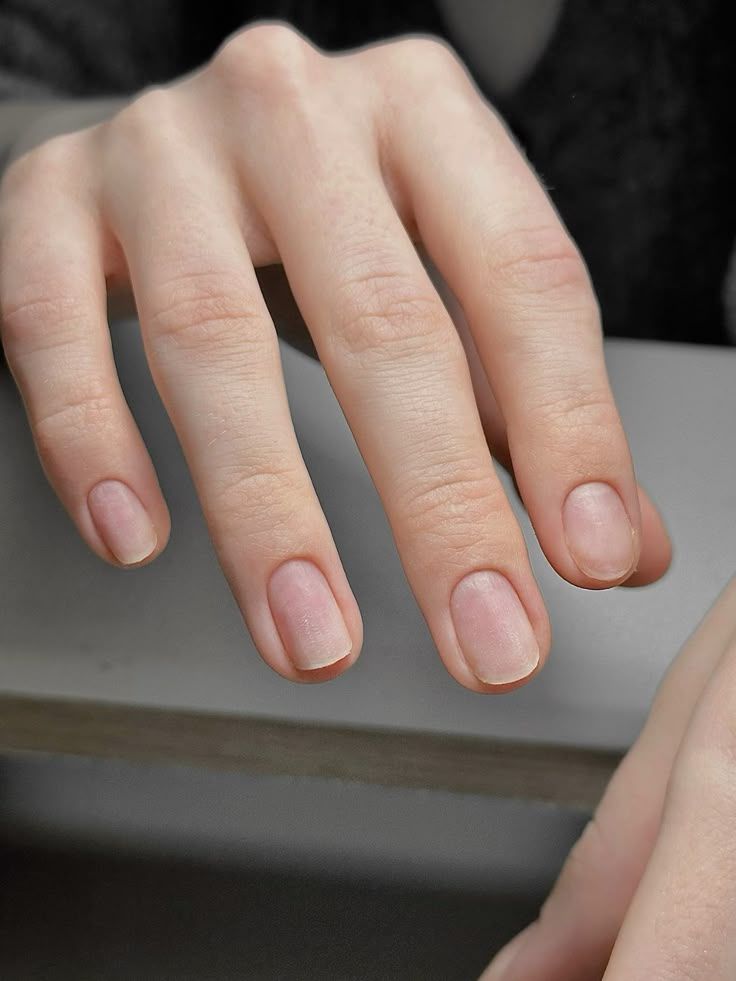 Close-up of natural unpolished fingernails on a gray surface.