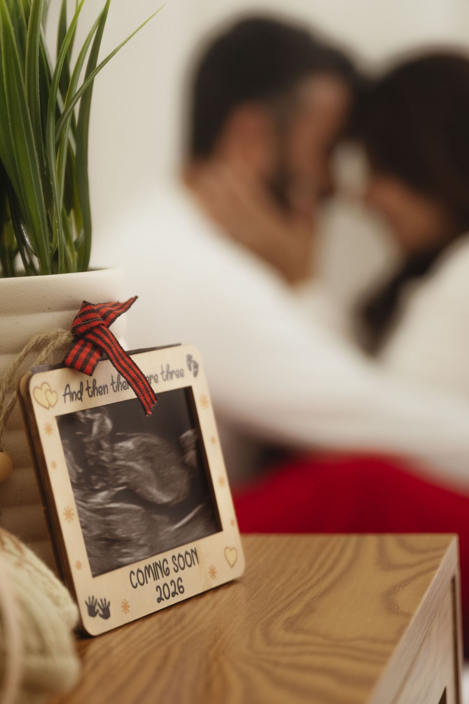 Ultrasound photos displayed on wooden surface with green plant in background.