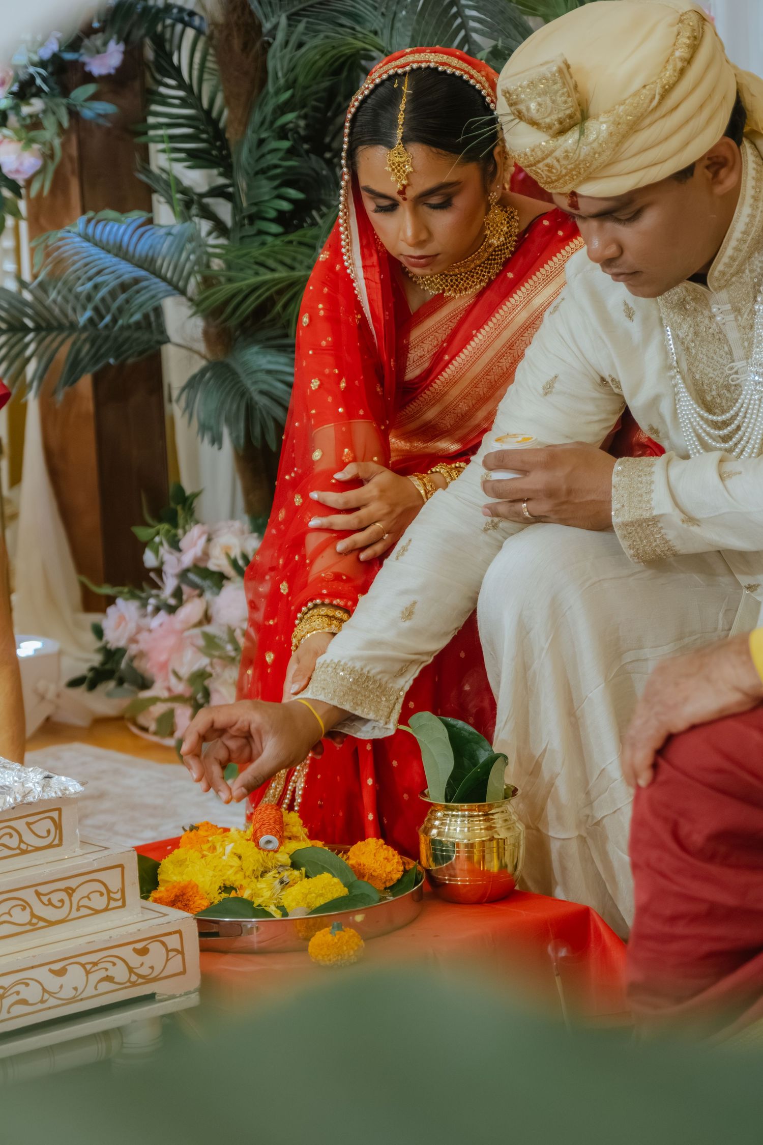 Indian bride in red saree and groom in white sherwani performing traditional Hindu wedding ceremony rituals.