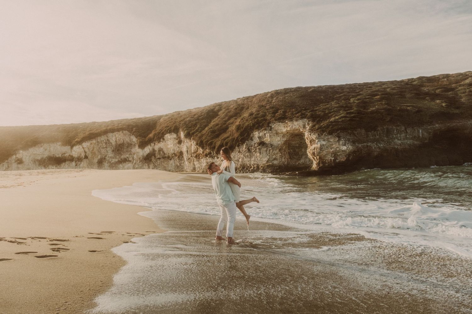Scenic coastal cliffs and beach landscape at sunset with warm golden light.