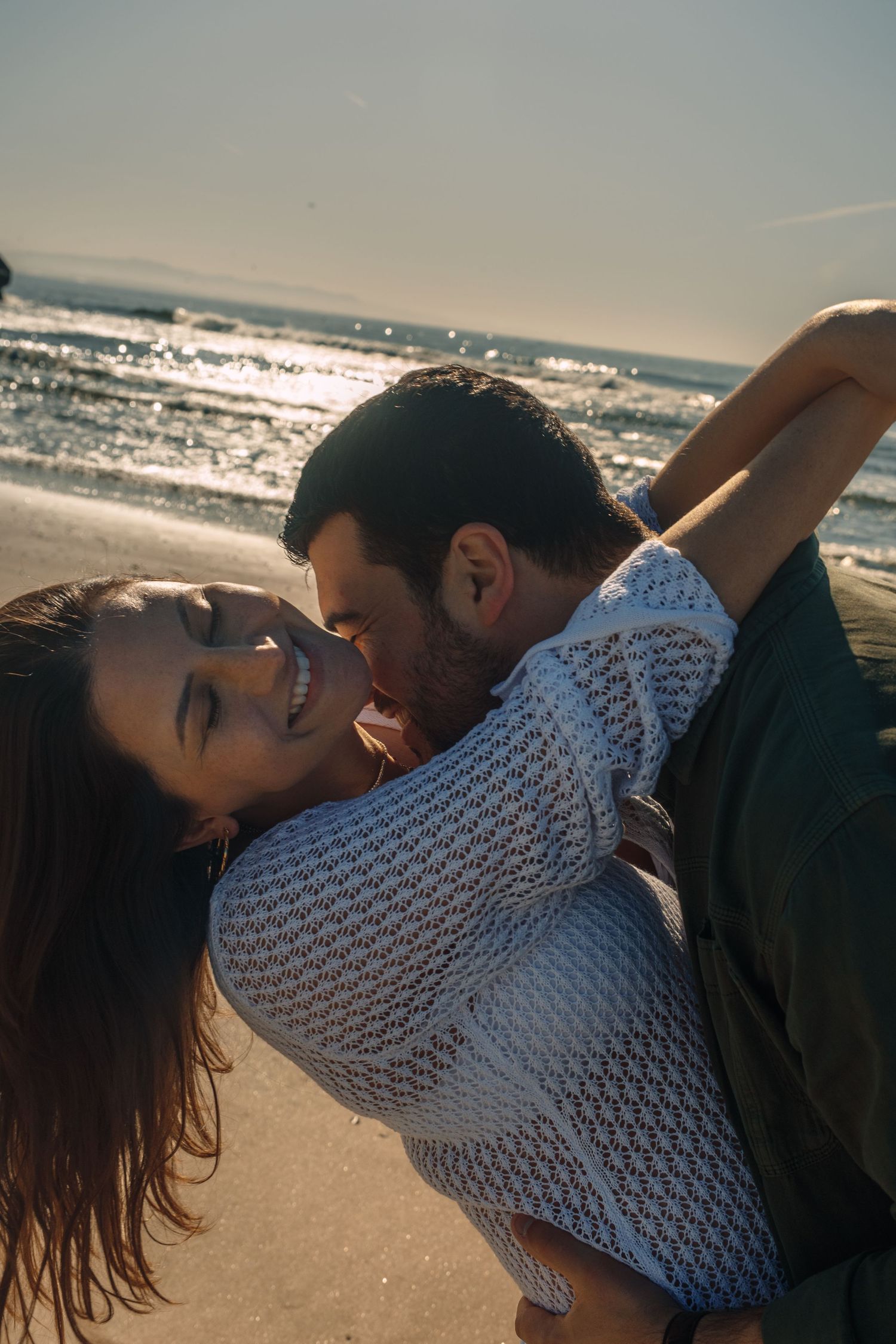 A romantic sequence showing tender moments between a couple on a sunny beach.