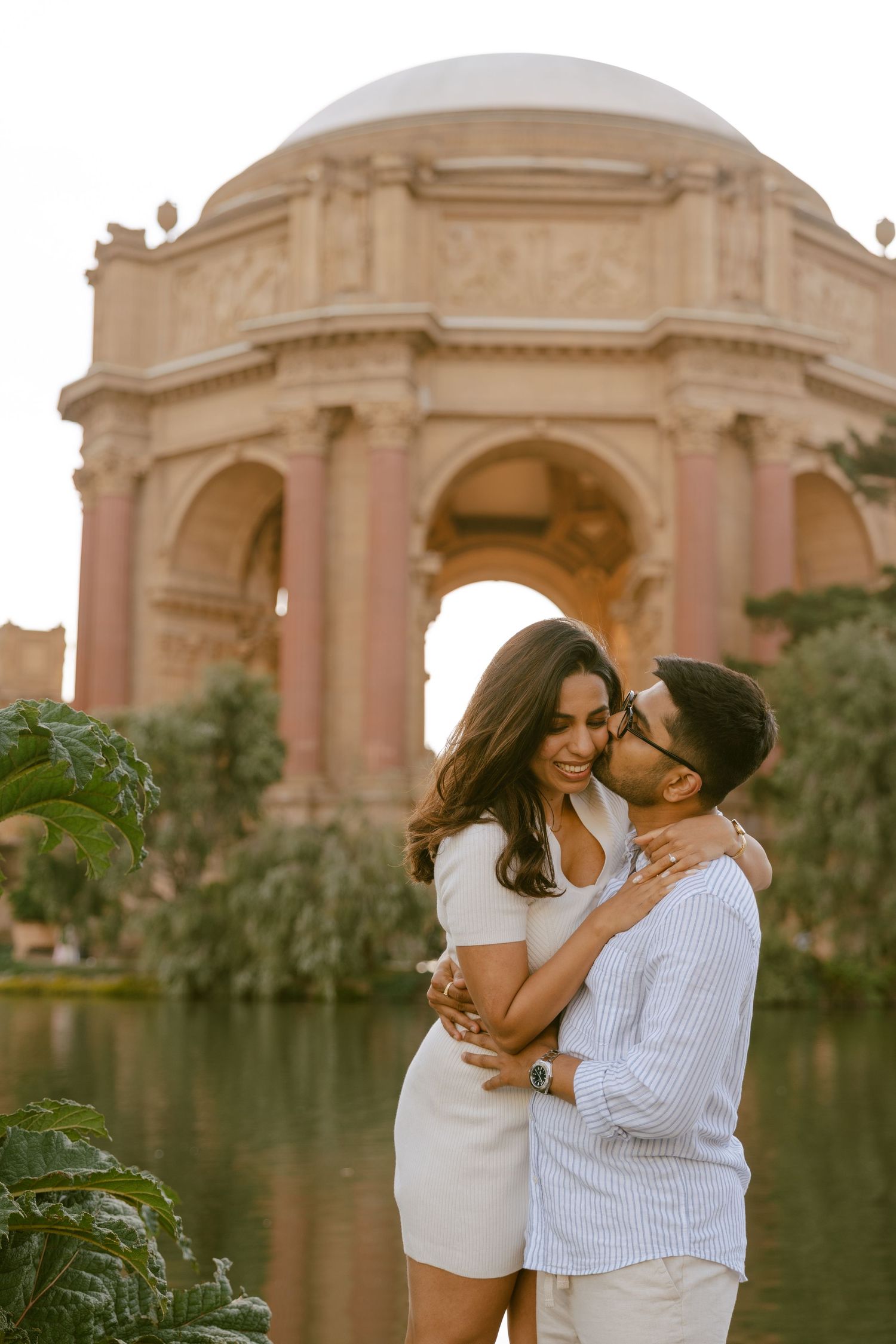 Couple embracing romantically in front of the Palace of Fine Arts dome in San Francisco.