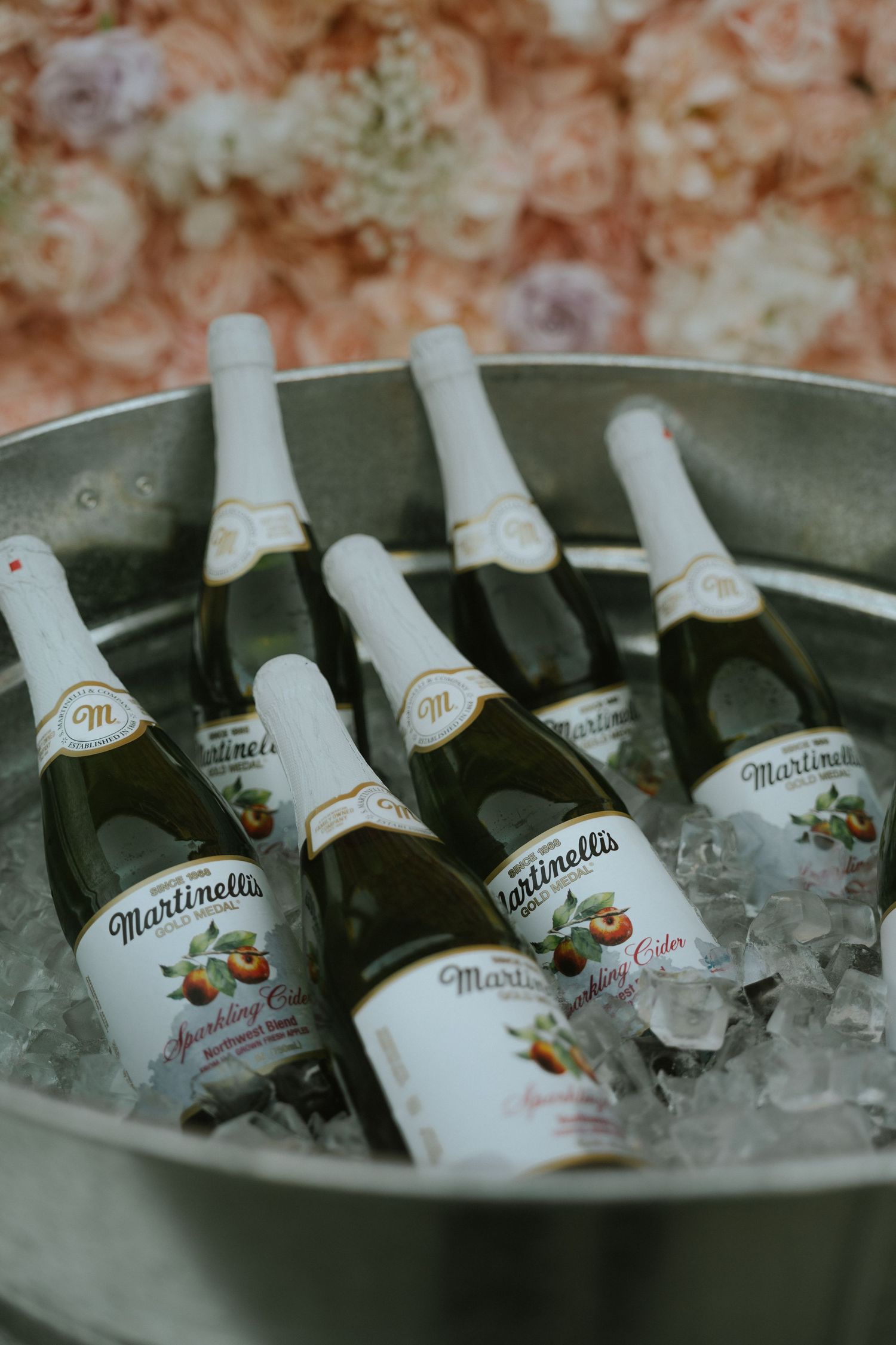 Martinelli's sparkling cider bottles chilling on ice in a metal bucket at a wedding reception.