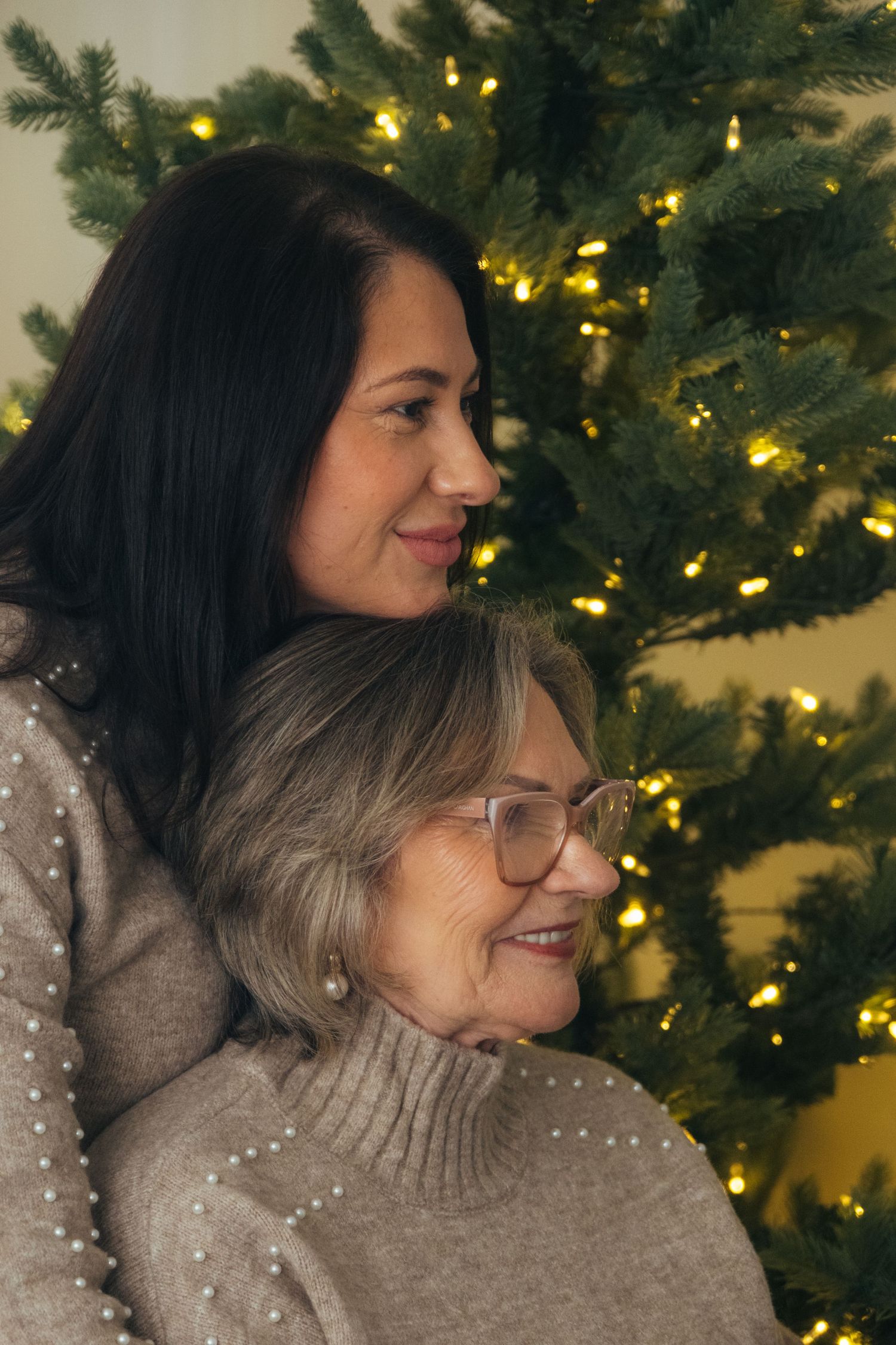 Tender moment captured in profile against lit Christmas tree background.