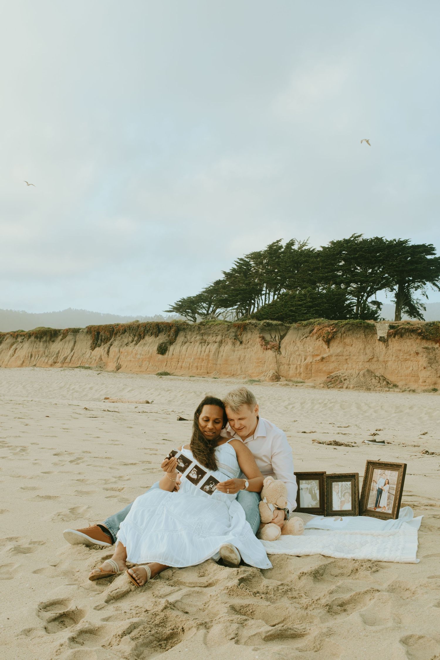 A couple lounges on the beach with wooden letter props.