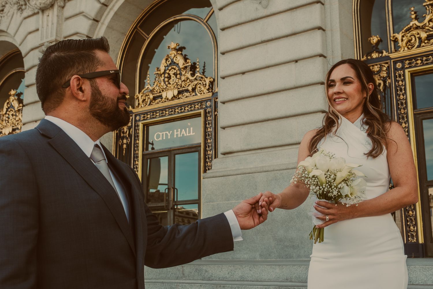Romantic moments captured in front of City Hall's ornate golden doorway.