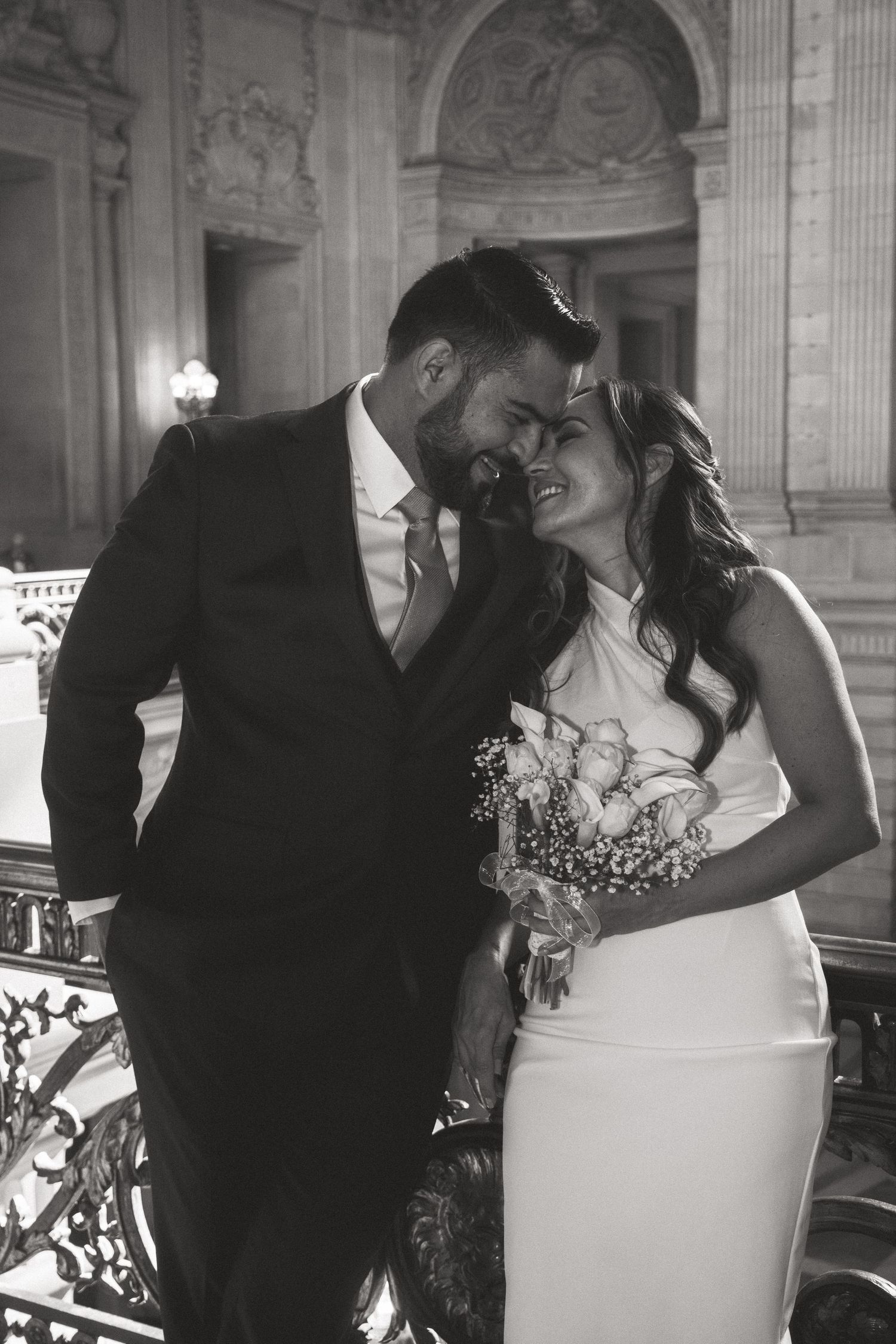 A romantic black and white wedding photo of a couple sharing an intimate moment in an elegant venue.