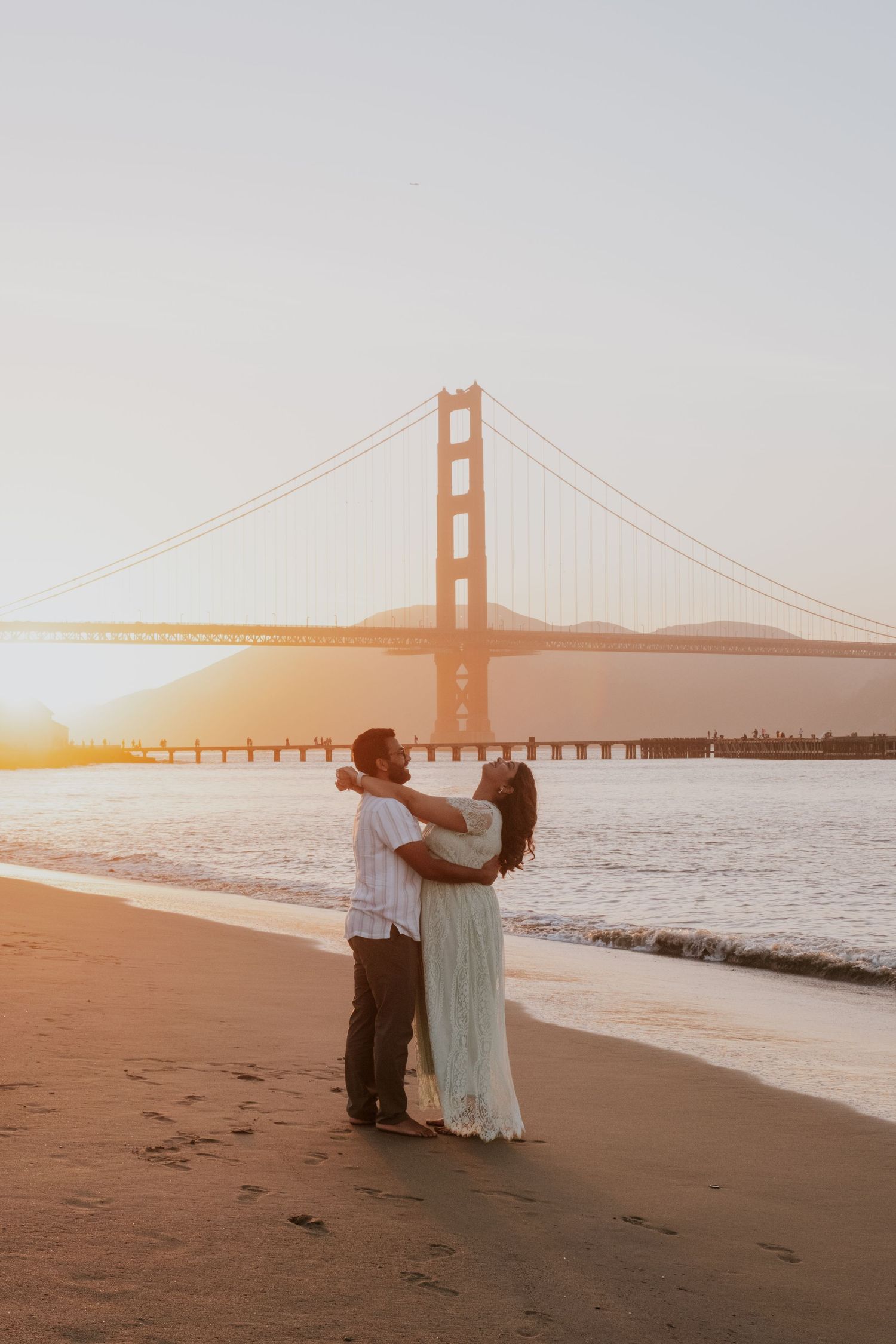A romantic sunset photoshoot at the Golden Gate Bridge with a couple silhouetted against the orange sky.
