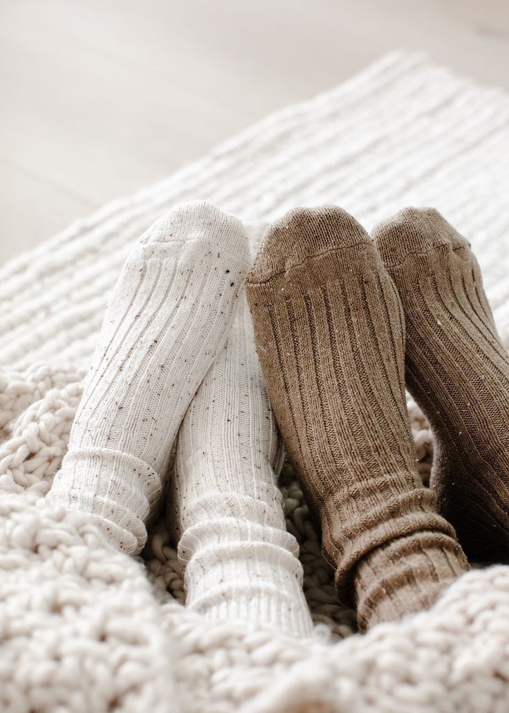 Two pairs of cozy wool socks in white and brown rest side by side on a plush carpet.