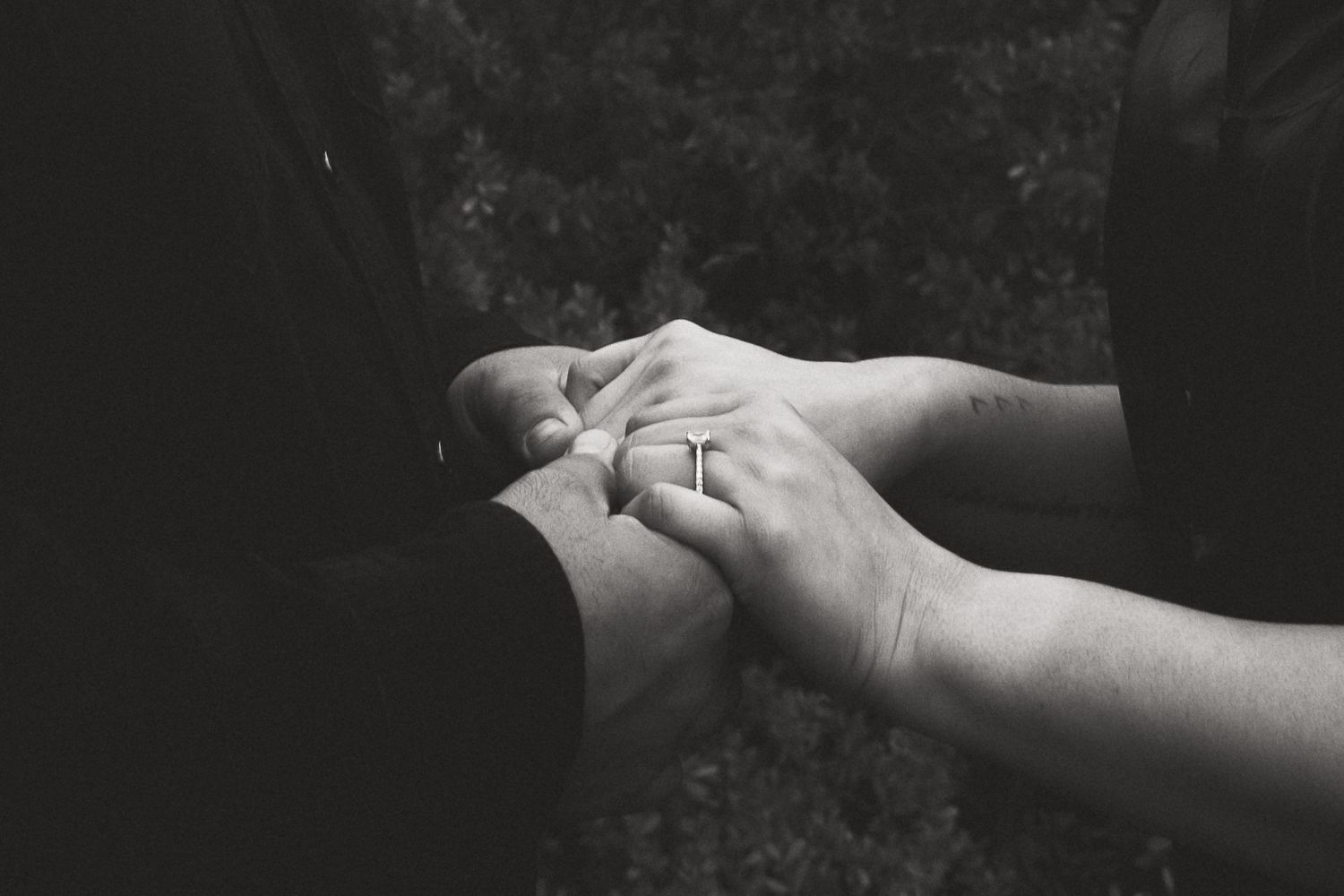 Close-up of hands reaching towards each other in black and white photography.