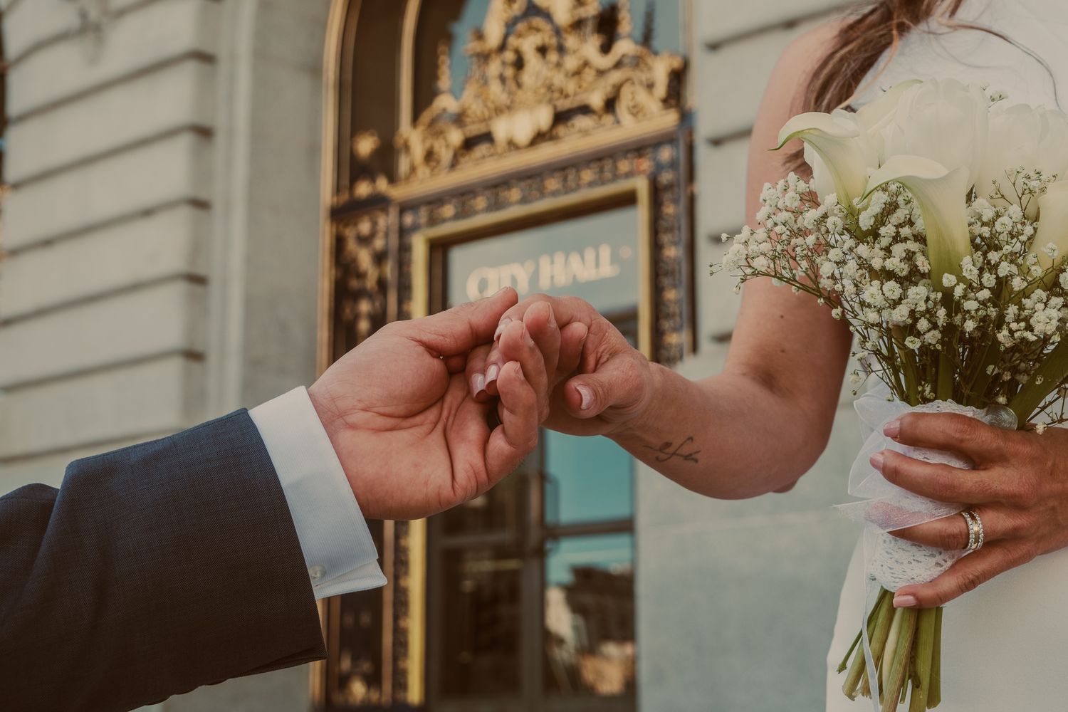 Close-up details of hands exchanging rings during a wedding ceremony at City Hall.