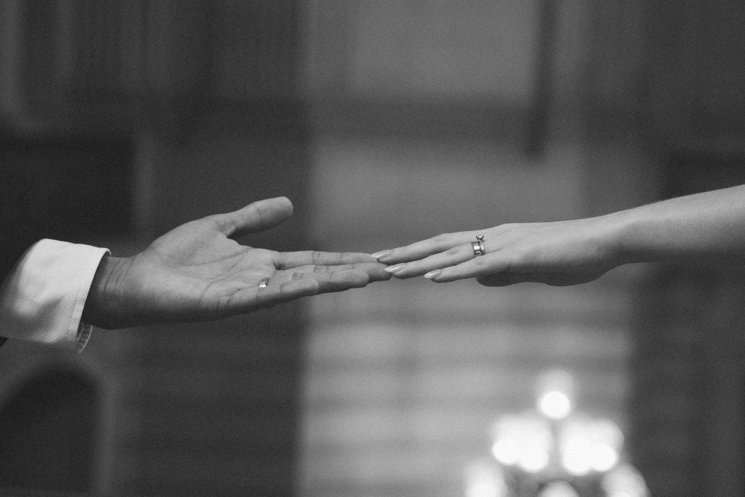 Black and white photo of hands reaching towards each other across a blurred background.