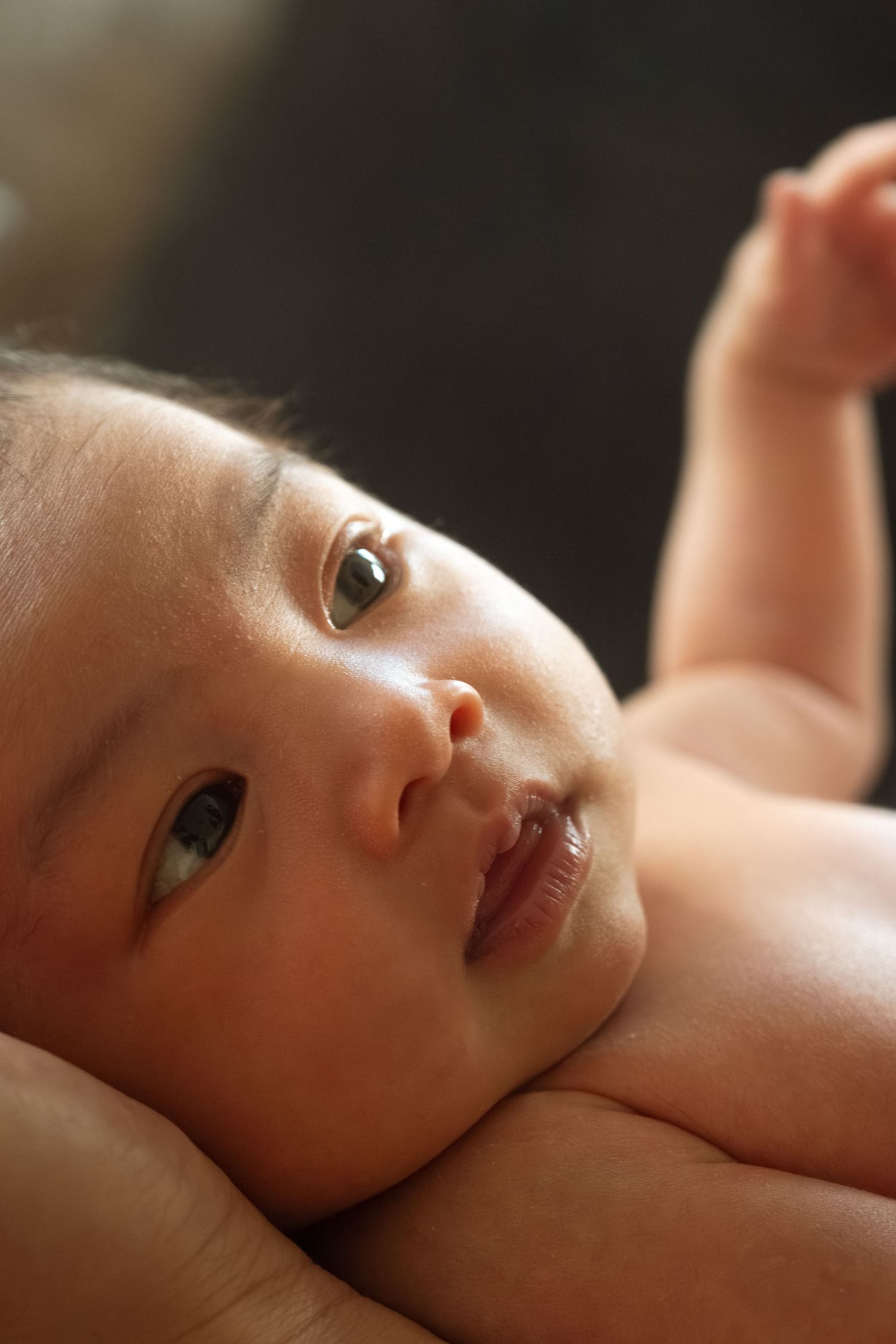 Close up portrait of a baby lying down with soft natural lighting highlighting their gentle features and expression.