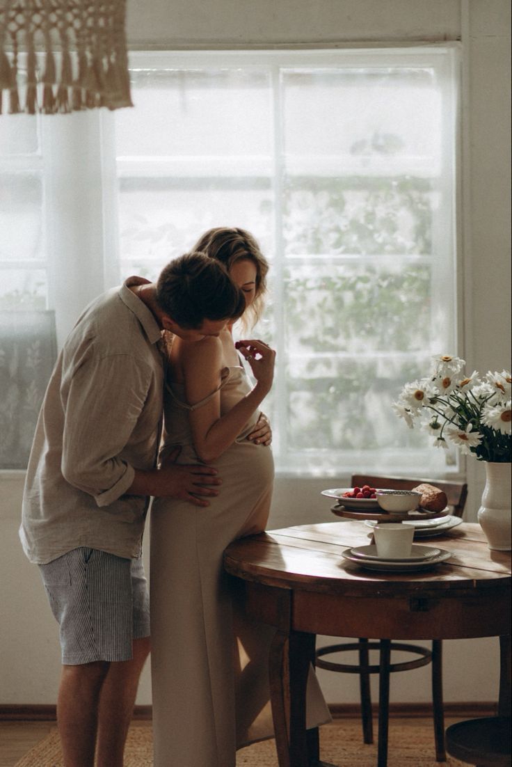 Romantic couple sharing tender moment at breakfast table with flowers and coffee.