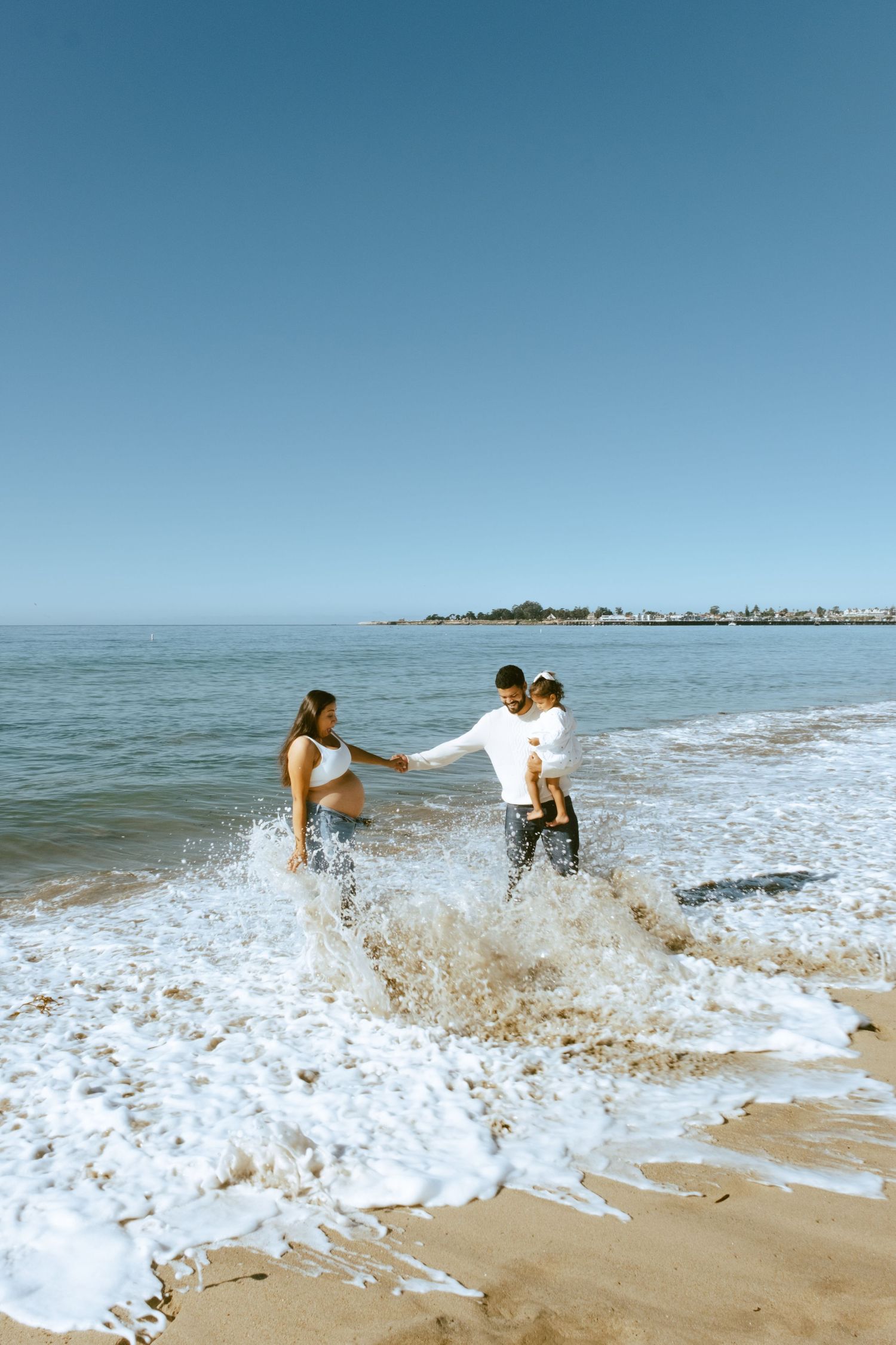 Friends enjoying a playful moment splashing in ocean waves on a sunny beach day.