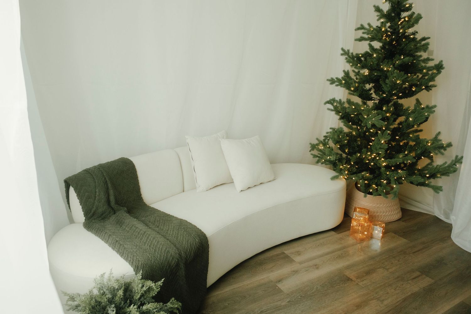 Modern white room with Christmas decor featuring a tree and comfortable seating.