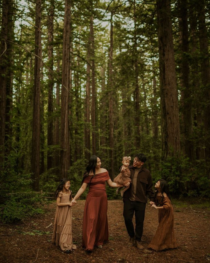 Group poses playfully in moody forest setting wearing earth-toned dresses.
